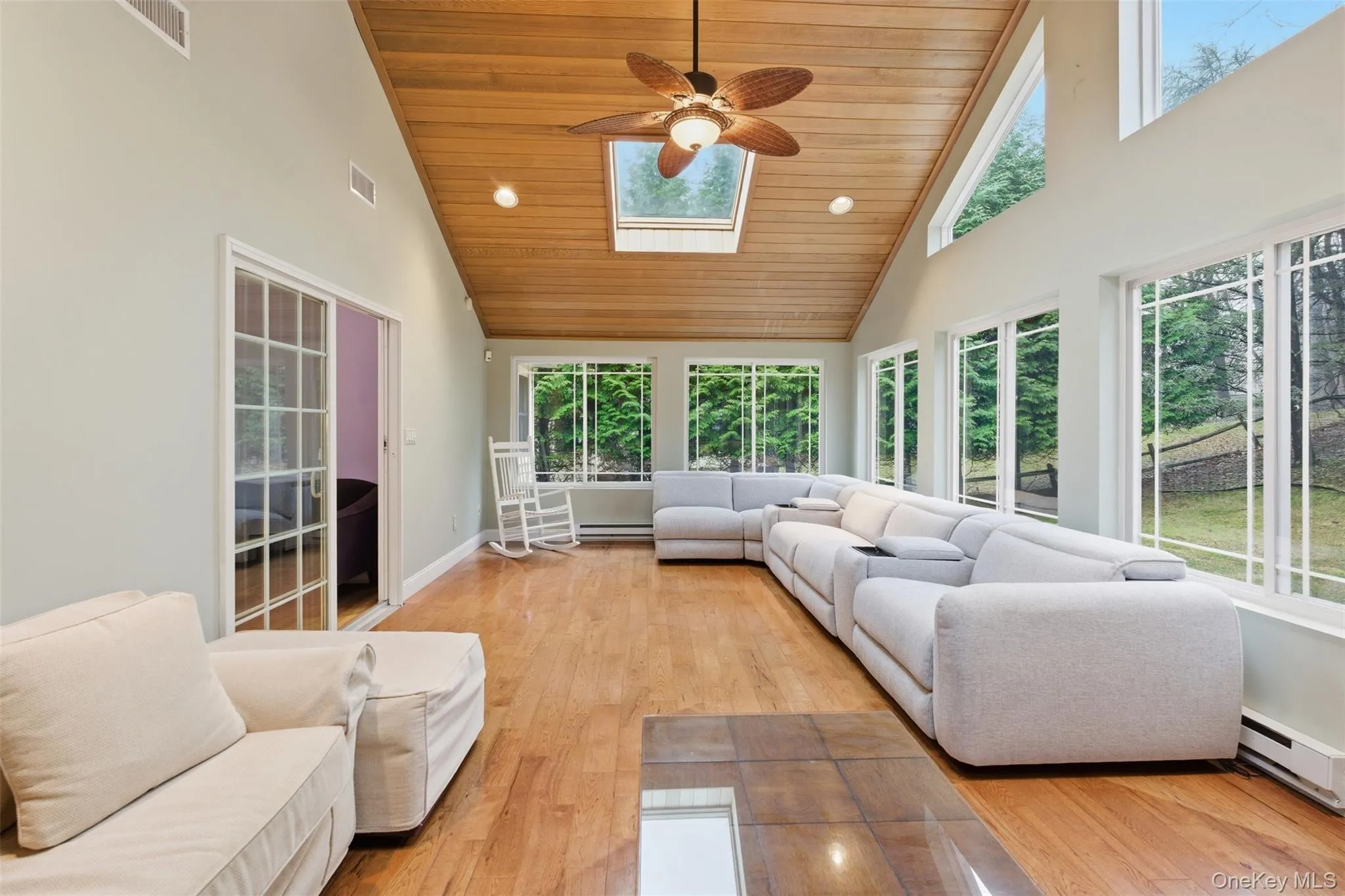Sunroom / solarium with a vaulted wooden ceiling, a skylight, wood finished floors, a baseboard radiator, and recessed lighting Sunroom / solarium with a vaulted wooden ceiling, a skylight, wood finished floors, a baseboard radiator, and recessed lighting