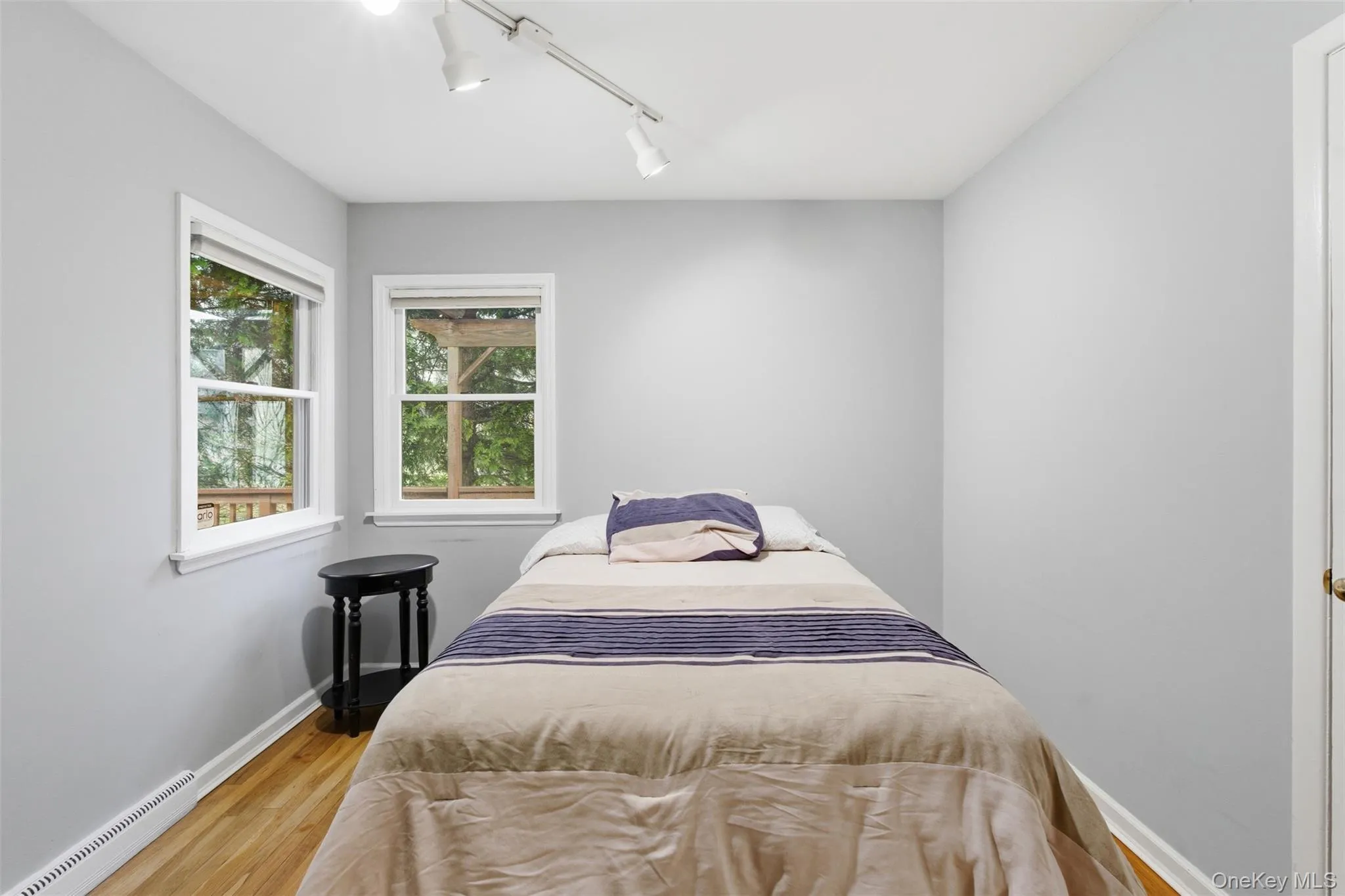 Bedroom with track lighting, baseboard heating, and wood finished floors Bedroom with track lighting, baseboard heating, and wood finished floors