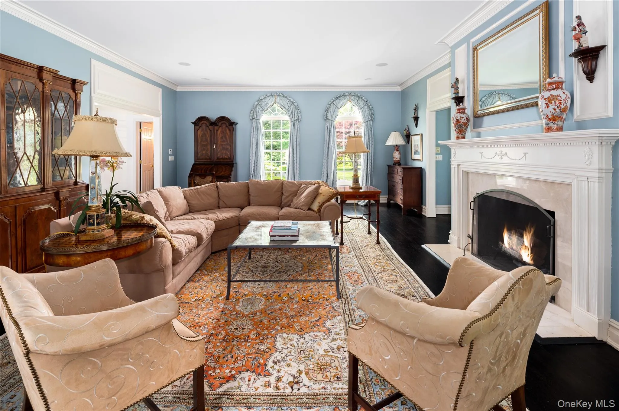 Living room with a fireplace, ornamental molding, wood finished floors, and baseboards Living room with a fireplace, ornamental molding, wood finished floors, and baseboards