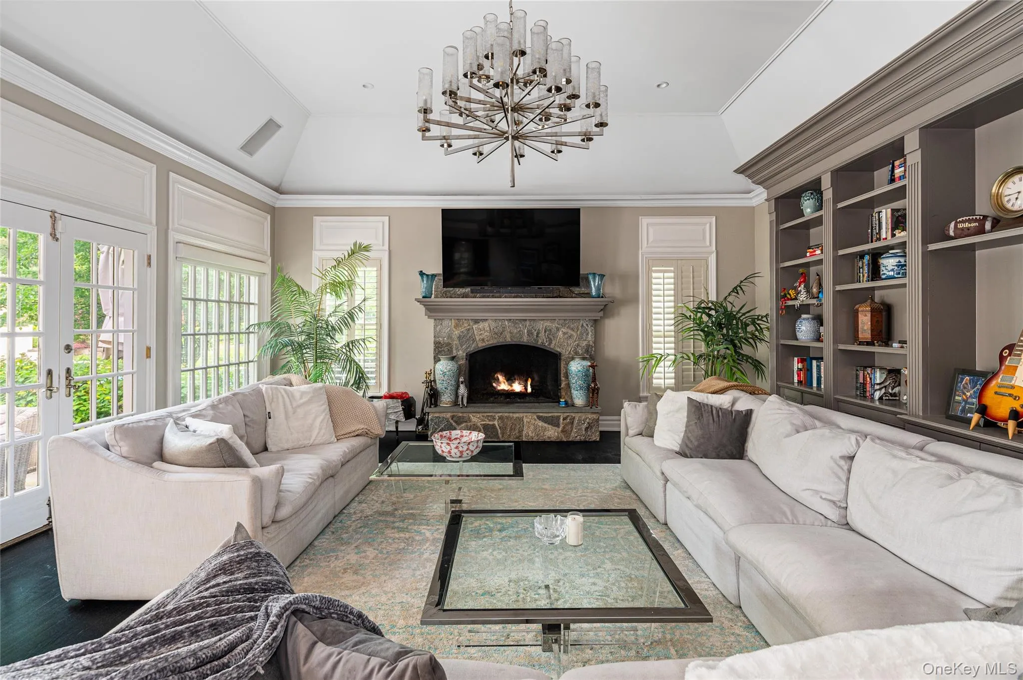 Living area featuring plenty of natural light, a fireplace, a chandelier, and french doors Living area featuring plenty of natural light, a fireplace, a chandelier, and french doors