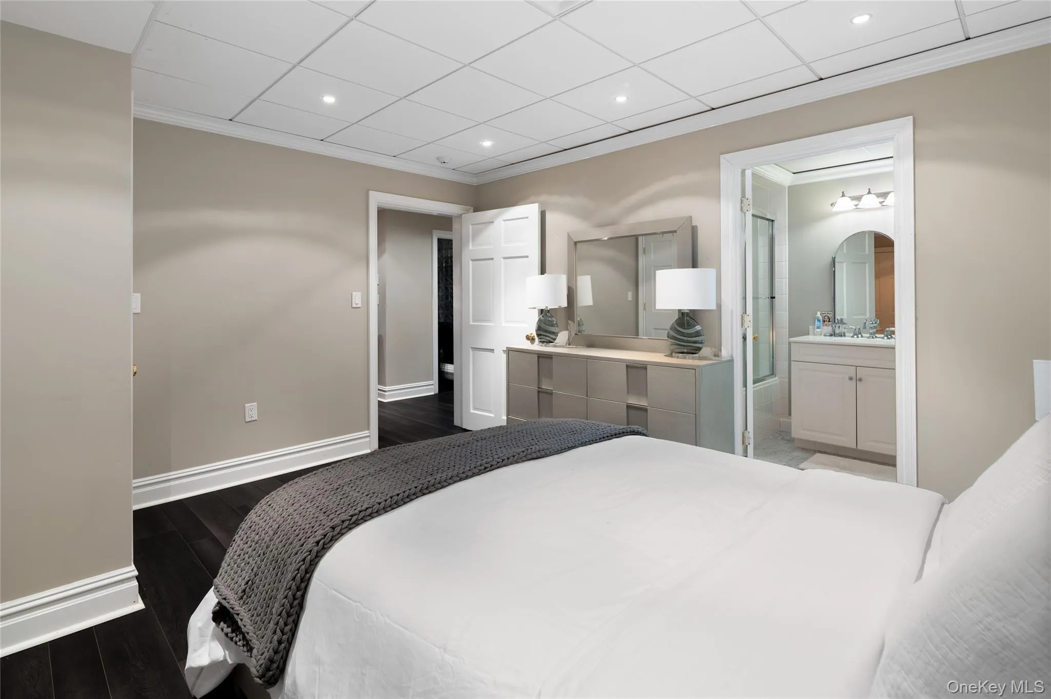 Bedroom with baseboards, dark wood-style floors, crown molding, recessed lighting, and ensuite bath Bedroom with baseboards, dark wood-style floors, crown molding, recessed lighting, and ensuite bath