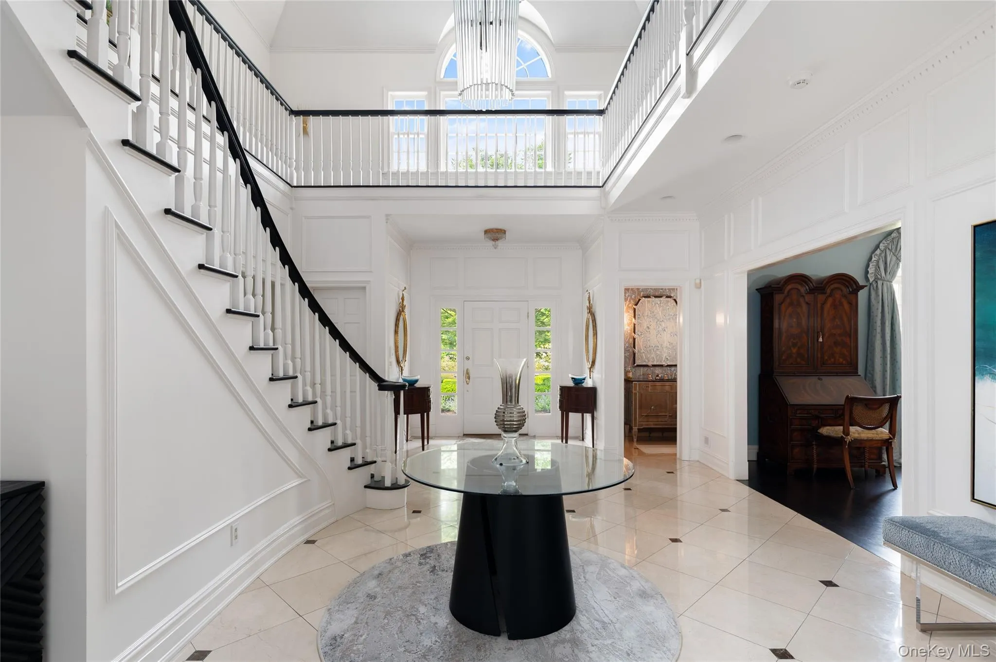 Entrance foyer with a towering ceiling, stairway, light tile patterned floors, a decorative wall, and a chandelier Entrance foyer with a towering ceiling, stairway, light tile patterned floors, a decorative wall, and a chandelier