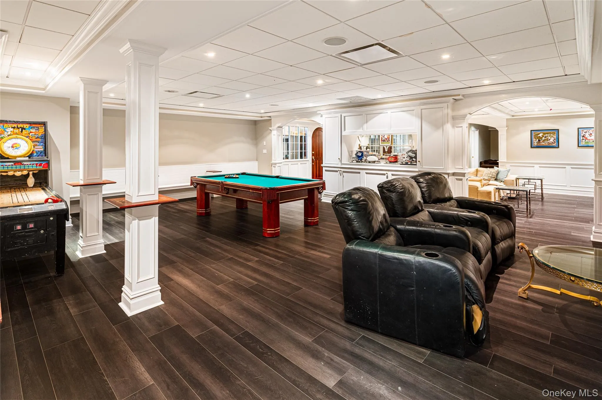 Playroom with ornate columns, arched walkways, a wainscoted wall, dark wood finished floors, and a decorative wall Playroom with ornate columns, arched walkways, a wainscoted wall, dark wood finished floors, and a decorative wall