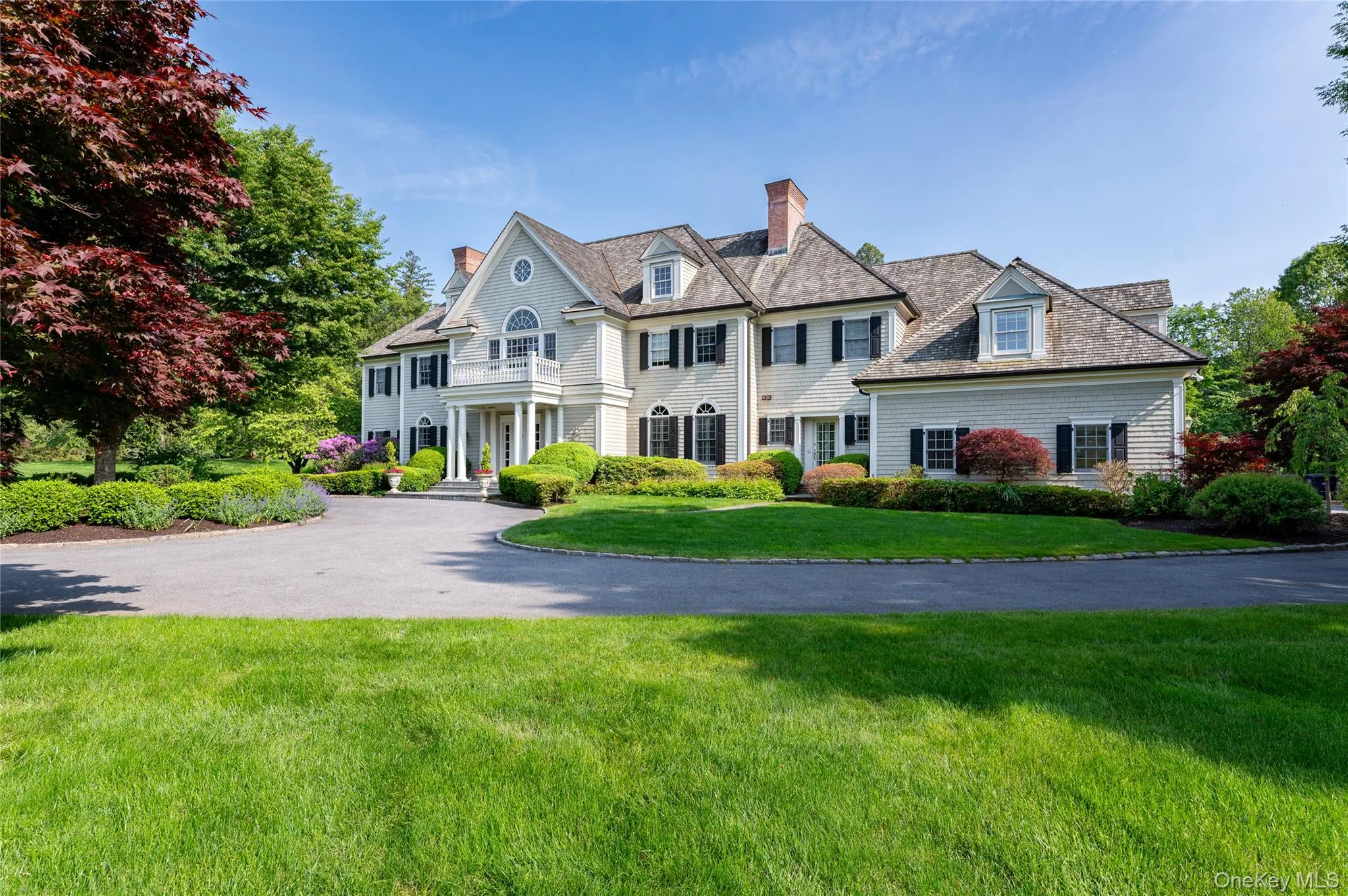 Shingle-style home featuring a chimney, a front lawn, and driveway Shingle-style home featuring a chimney, a front lawn, and driveway