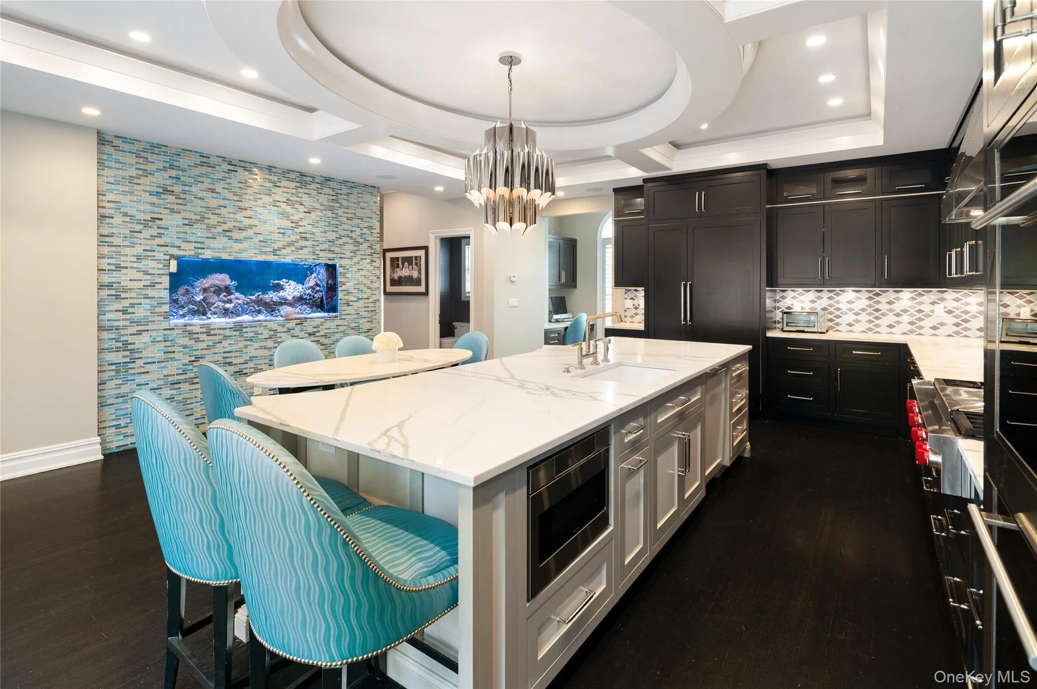 Kitchen featuring a sink, stainless steel appliances, a center island with sink, a breakfast bar, and dark wood-style floors Kitchen featuring a sink, stainless steel appliances, a center island with sink, a breakfast bar, and dark wood-style floors