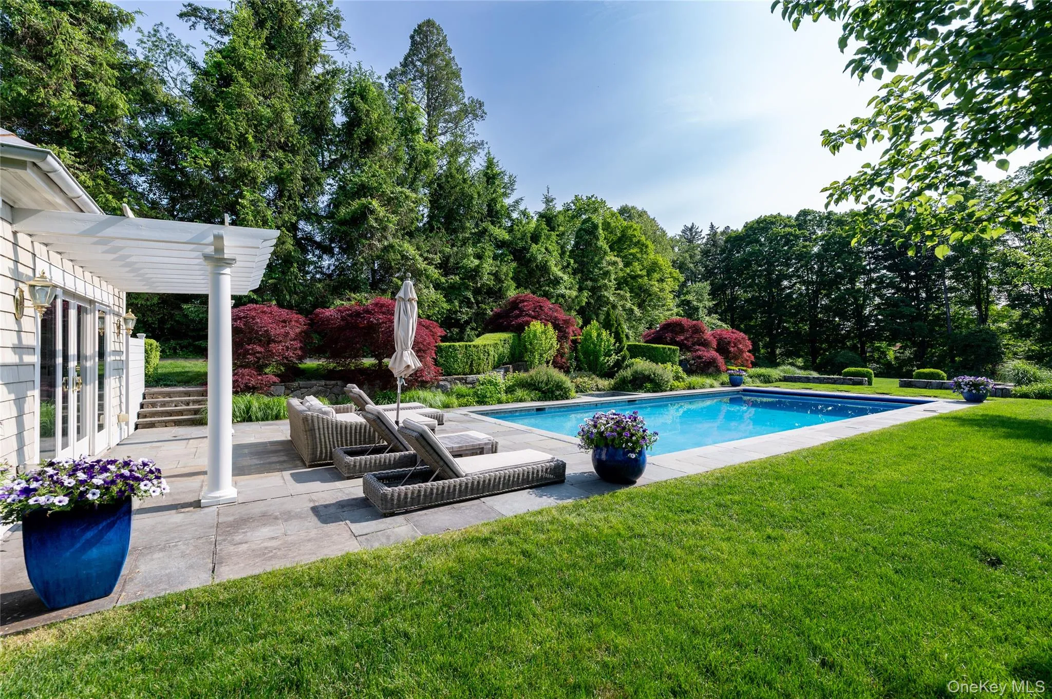 Outdoor pool with a yard, a patio area, and view of scattered trees Outdoor pool with a yard, a patio area, and view of scattered trees