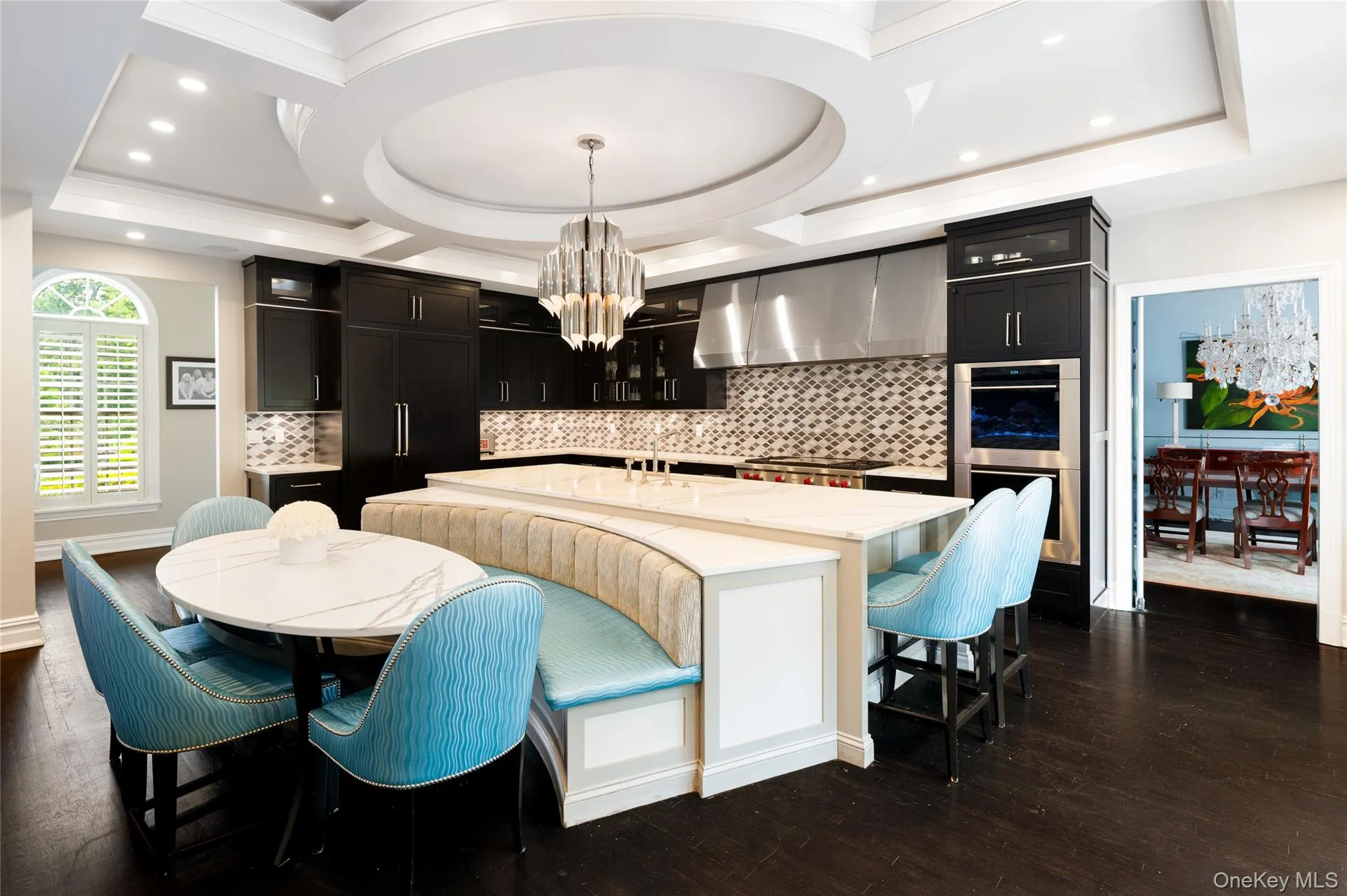 Kitchen with wall chimney range hood, a chandelier, stainless steel double oven, dark cabinets, and recessed lighting Kitchen with wall chimney range hood, a chandelier, stainless steel double oven, dark cabinets, and recessed lighting