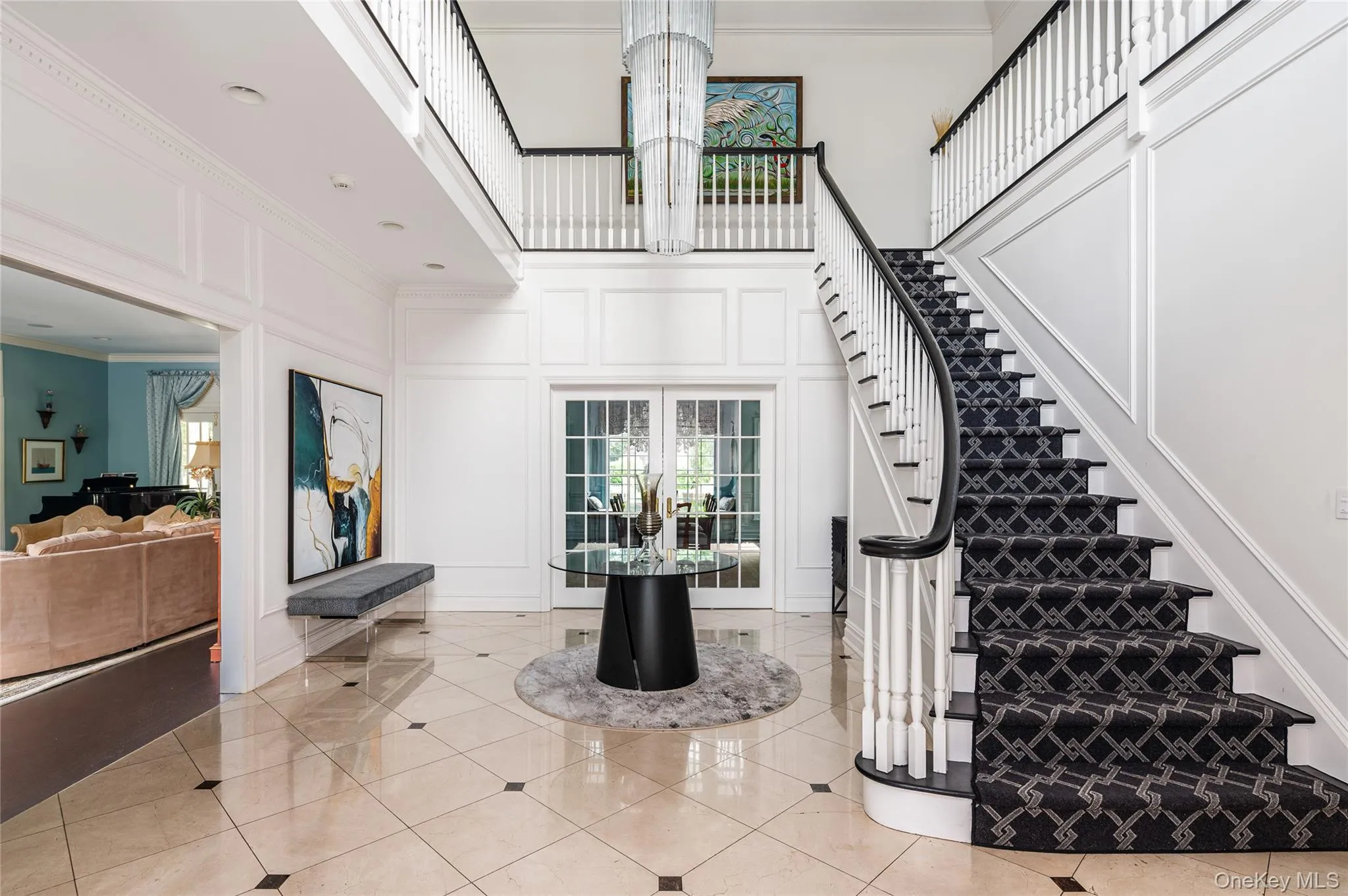 Staircase with a decorative wall, a high ceiling, plenty of natural light, ornamental molding, and a chandelier Staircase with a decorative wall, a high ceiling, plenty of natural light, ornamental molding, and a chandelier