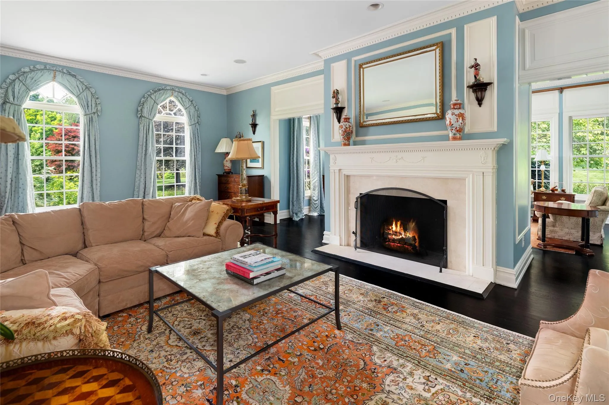 Living area featuring a high end fireplace, wood finished floors, crown molding, and baseboards Living area featuring a high end fireplace, wood finished floors, crown molding, and baseboards