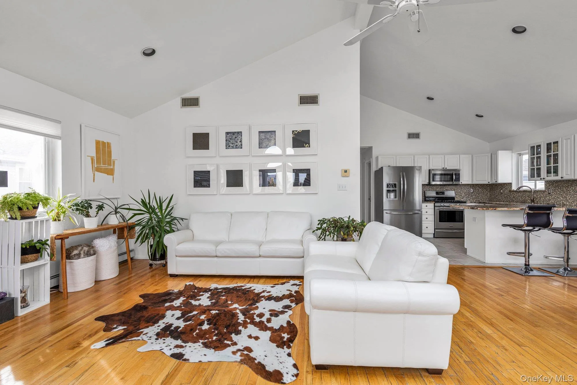 Living room with light wood finished floors, ceiling fan, and vaulted ceiling Living room with light wood finished floors, ceiling fan, and vaulted ceiling