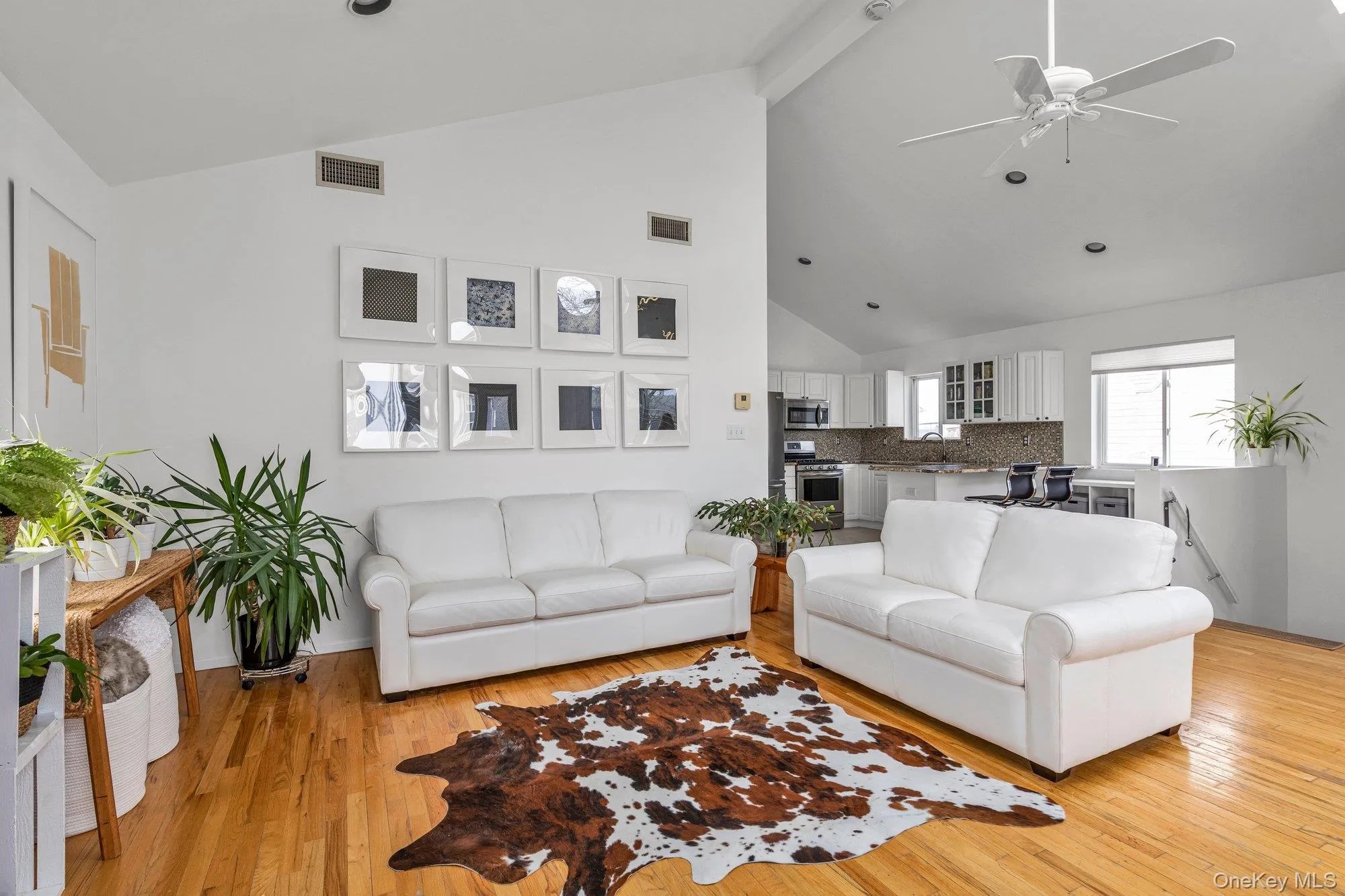 Living room featuring ceiling fan, light wood finished floors, and vaulted ceiling Living room featuring ceiling fan, light wood finished floors, and vaulted ceiling