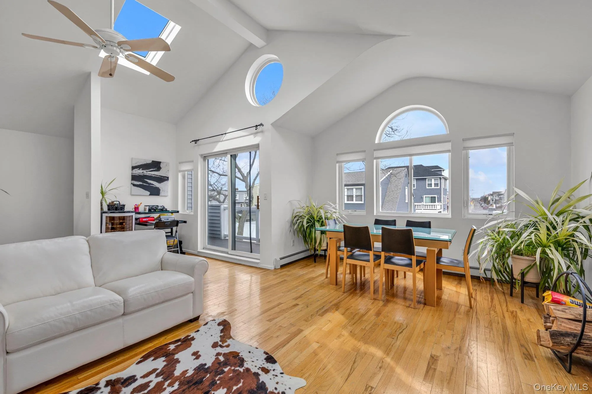 Living room featuring light wood-style floors, a ceiling fan, healthy amount of natural light, and a baseboard radiator Living room featuring light wood-style floors, a ceiling fan, healthy amount of natural light, and a baseboard radiator