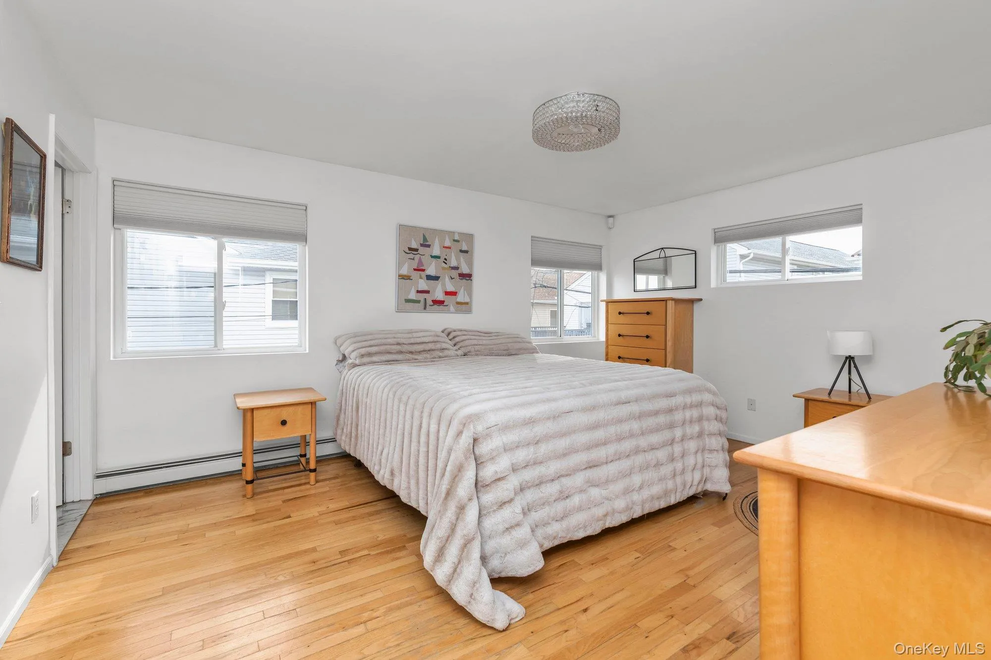 Bedroom with light wood finished floors and a baseboard heating unit Bedroom with light wood finished floors and a baseboard heating unit
