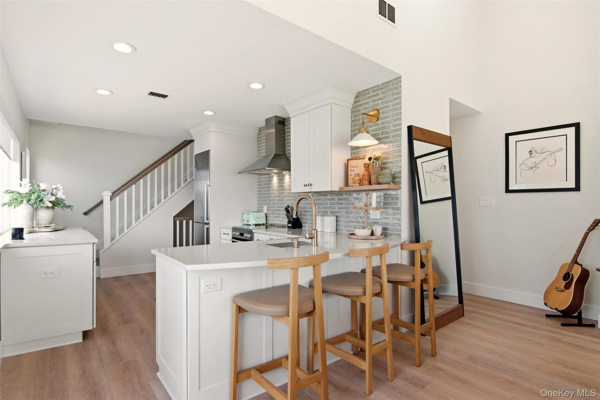 Kitchen featuring light wood-style flooring, a kitchen breakfast bar, a peninsula, white cabinetry, and open shelves Kitchen featuring light wood-style flooring, a kitchen breakfast bar, a peninsula, white cabinetry, and open shelves
