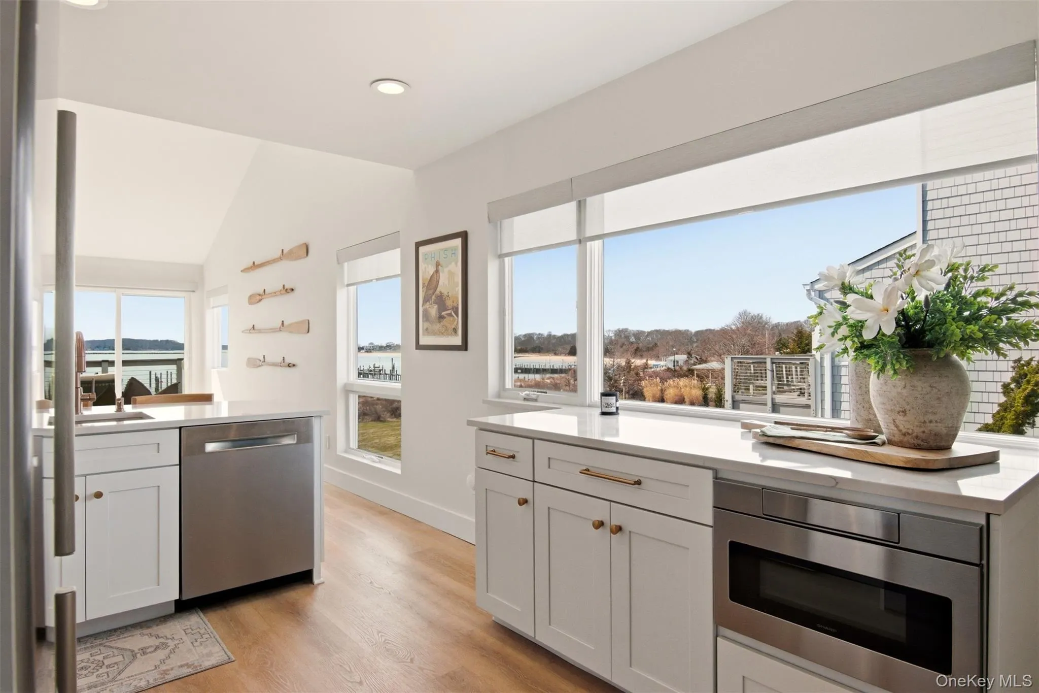 New kitchen with incredible views. Stainless steel appliances, white cabinetry, light wood-style floors, quartz counters, vaulted ceiling, and recessed lighting New kitchen with incredible views. Stainless steel appliances, white cabinetry, light wood-style floors, quartz counters, vaulted ceiling, and recessed lighting