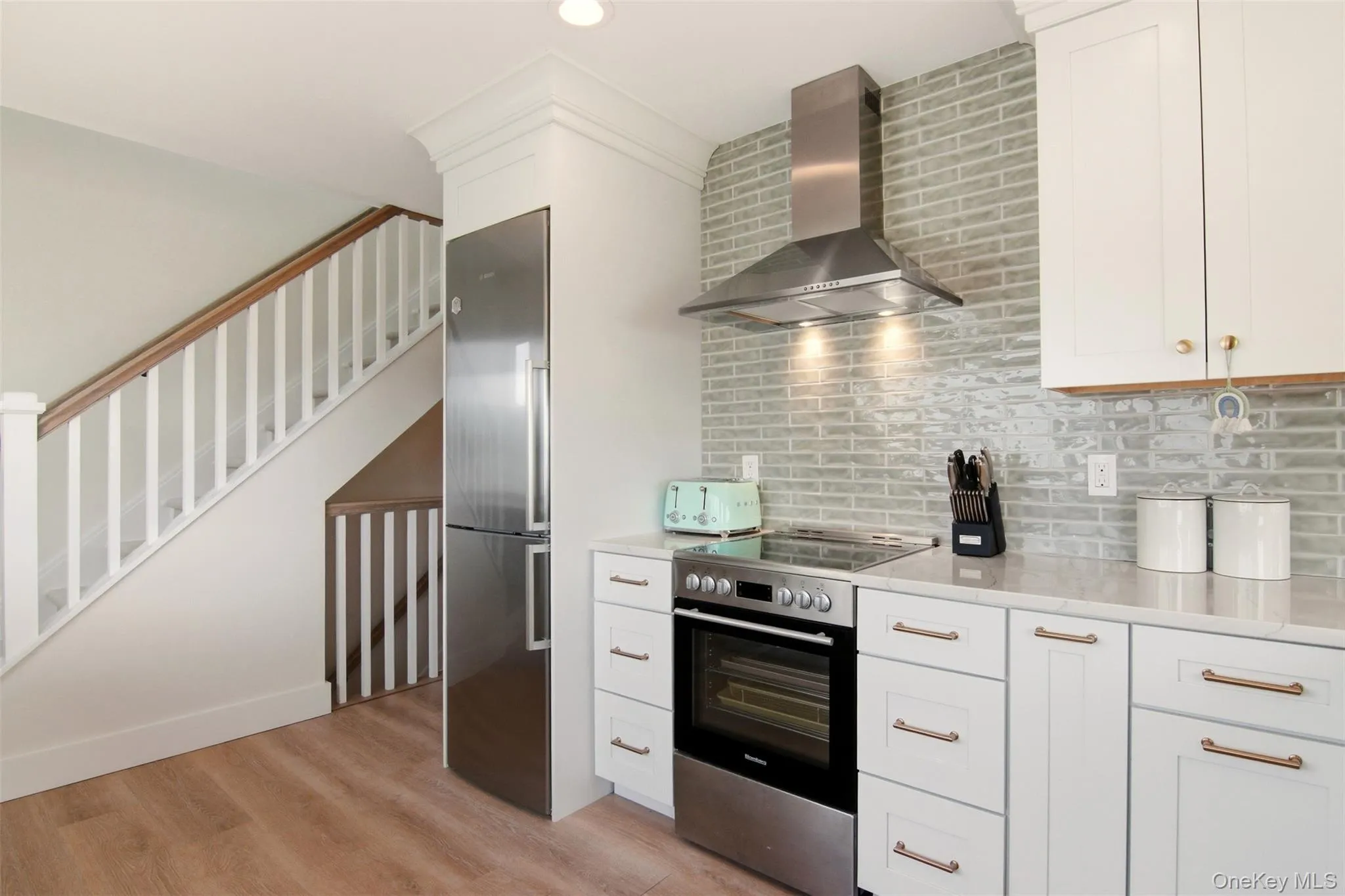 New kitchen with incredible views. Stainless steel appliances, white cabinetry, light wood-style floors, quartz counters, vaulted ceiling, and recessed lighting New kitchen with incredible views. Stainless steel appliances, white cabinetry, light wood-style floors, quartz counters, vaulted ceiling, and recessed lighting