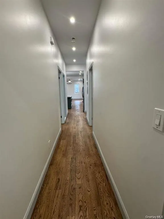 Hall with dark wood-style floors and baseboards Hall with dark wood-style floors and baseboards