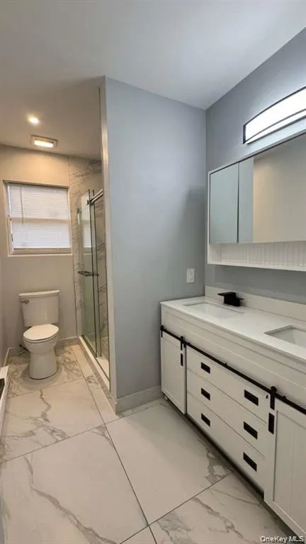 Bathroom featuring light marble finish floors, double vanity, and a stall shower Bathroom featuring light marble finish floors, double vanity, and a stall shower