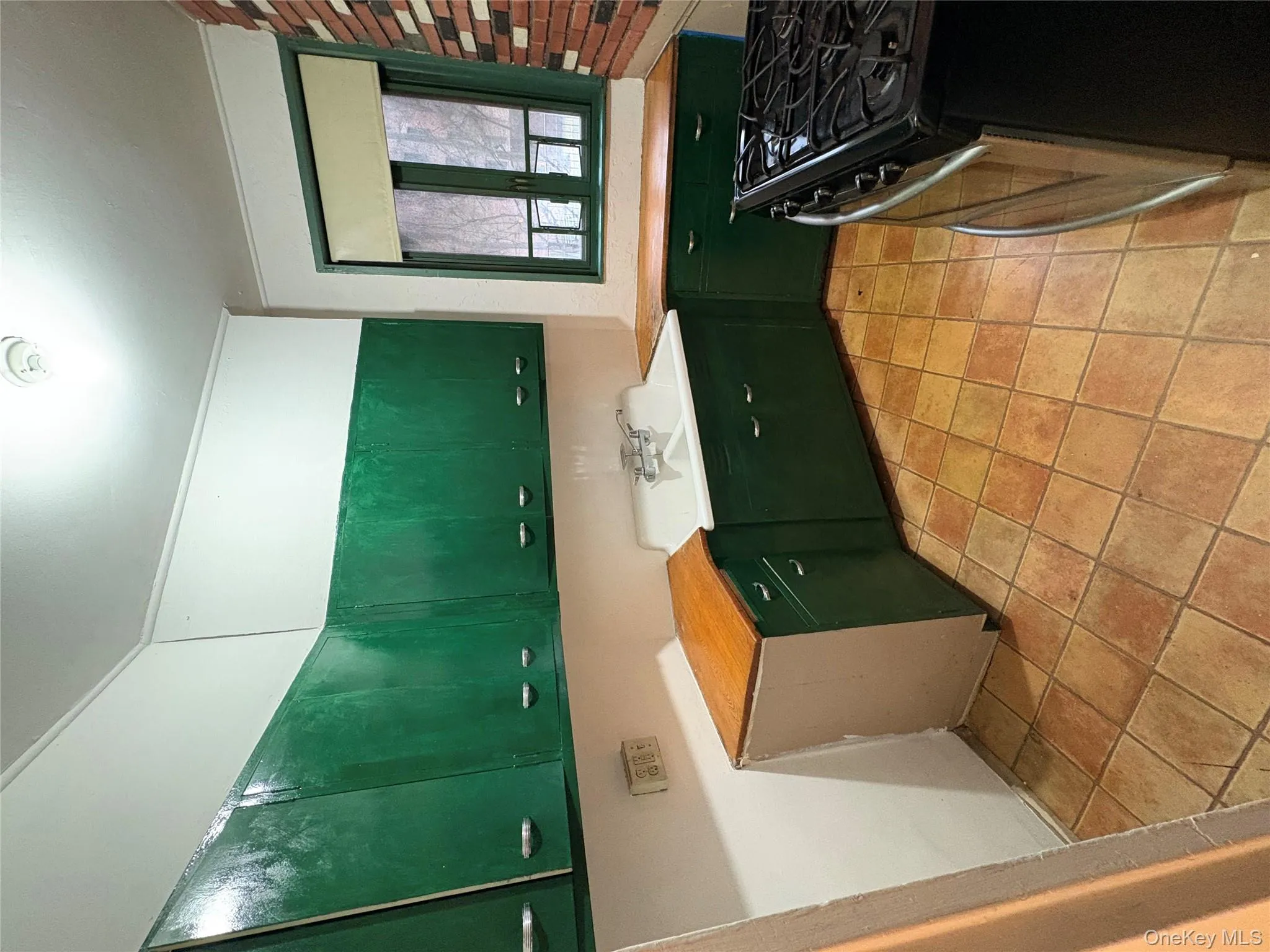 Kitchen featuring stainless steel gas range oven, green cabinetry, and light countertops Kitchen featuring stainless steel gas range oven, green cabinetry, and light countertops