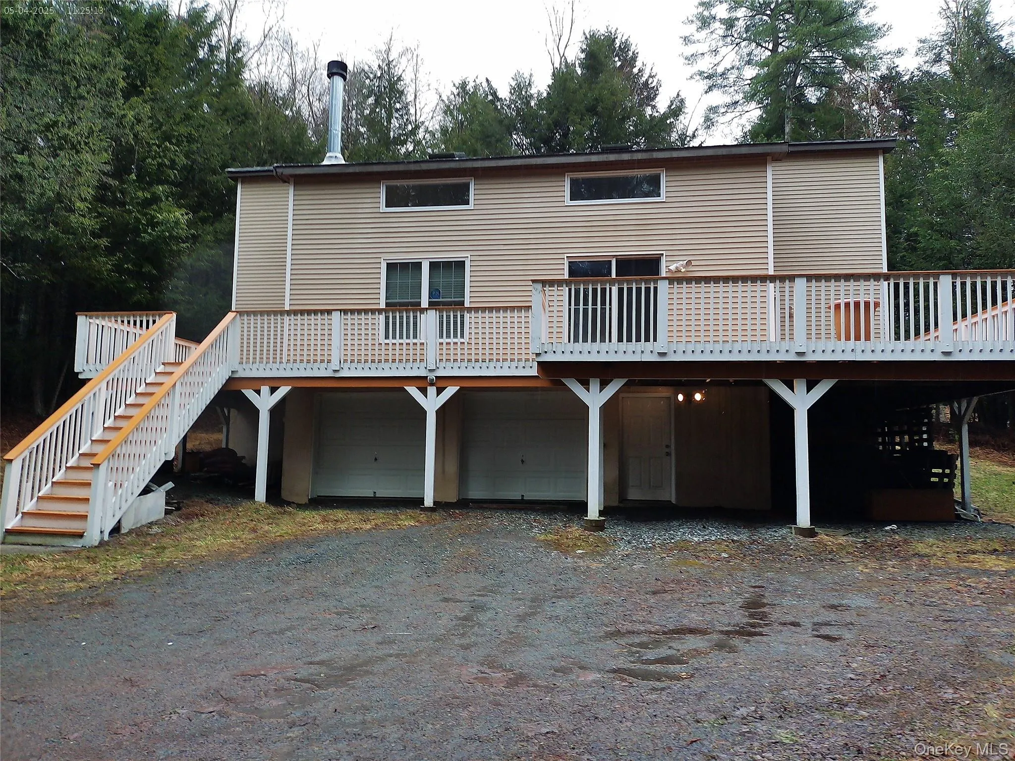 View of front of home featuring driveway, a wooden deck, a garage, and stairway View of front of home featuring driveway, a wooden deck, a garage, and stairway