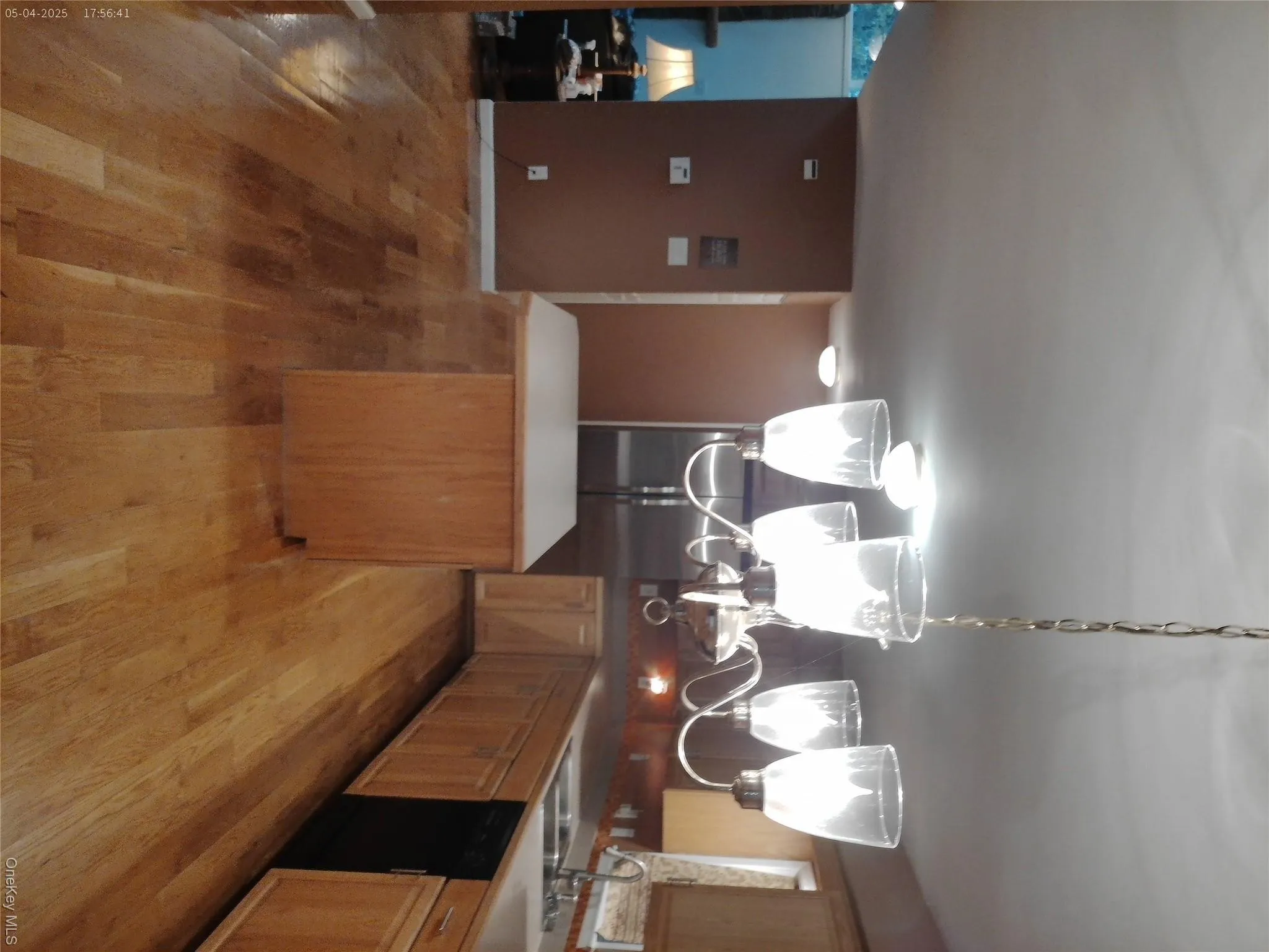 Kitchen featuring an inviting chandelier, a kitchen island, a sink, light wood-style floors, and dishwasher Kitchen featuring an inviting chandelier, a kitchen island, a sink, light wood-style floors, and dishwasher