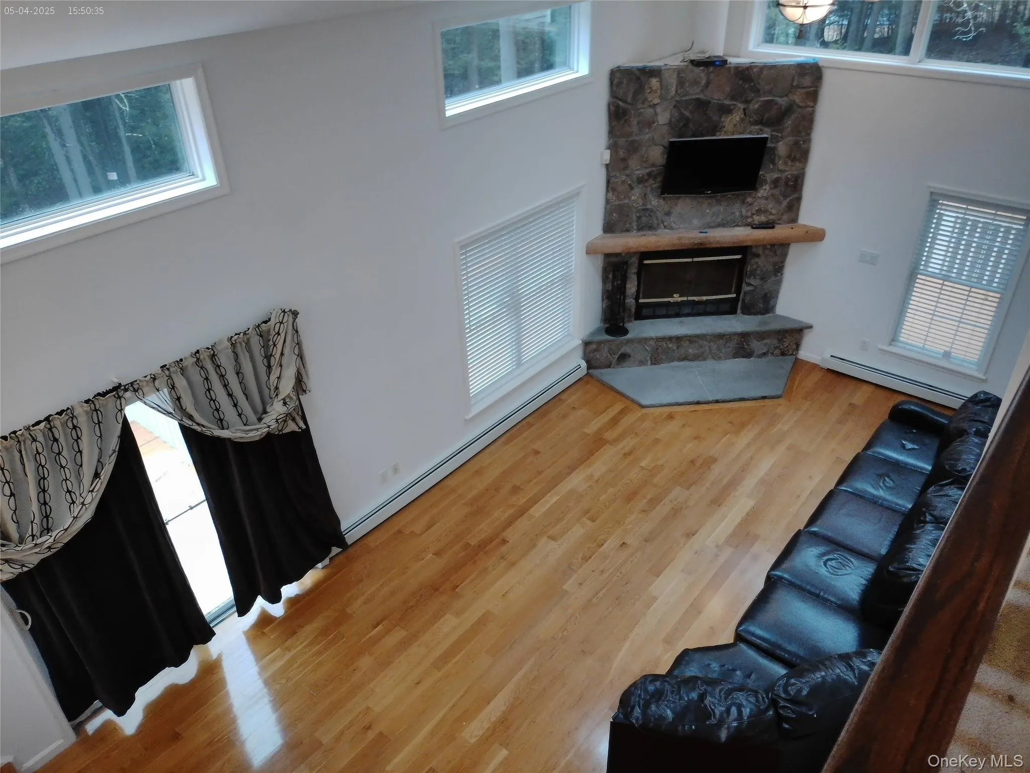Living area with a baseboard radiator, wood finished floors, a baseboard heating unit, and a healthy amount of sunlight Living area with a baseboard radiator, wood finished floors, a baseboard heating unit, and a healthy amount of sunlight