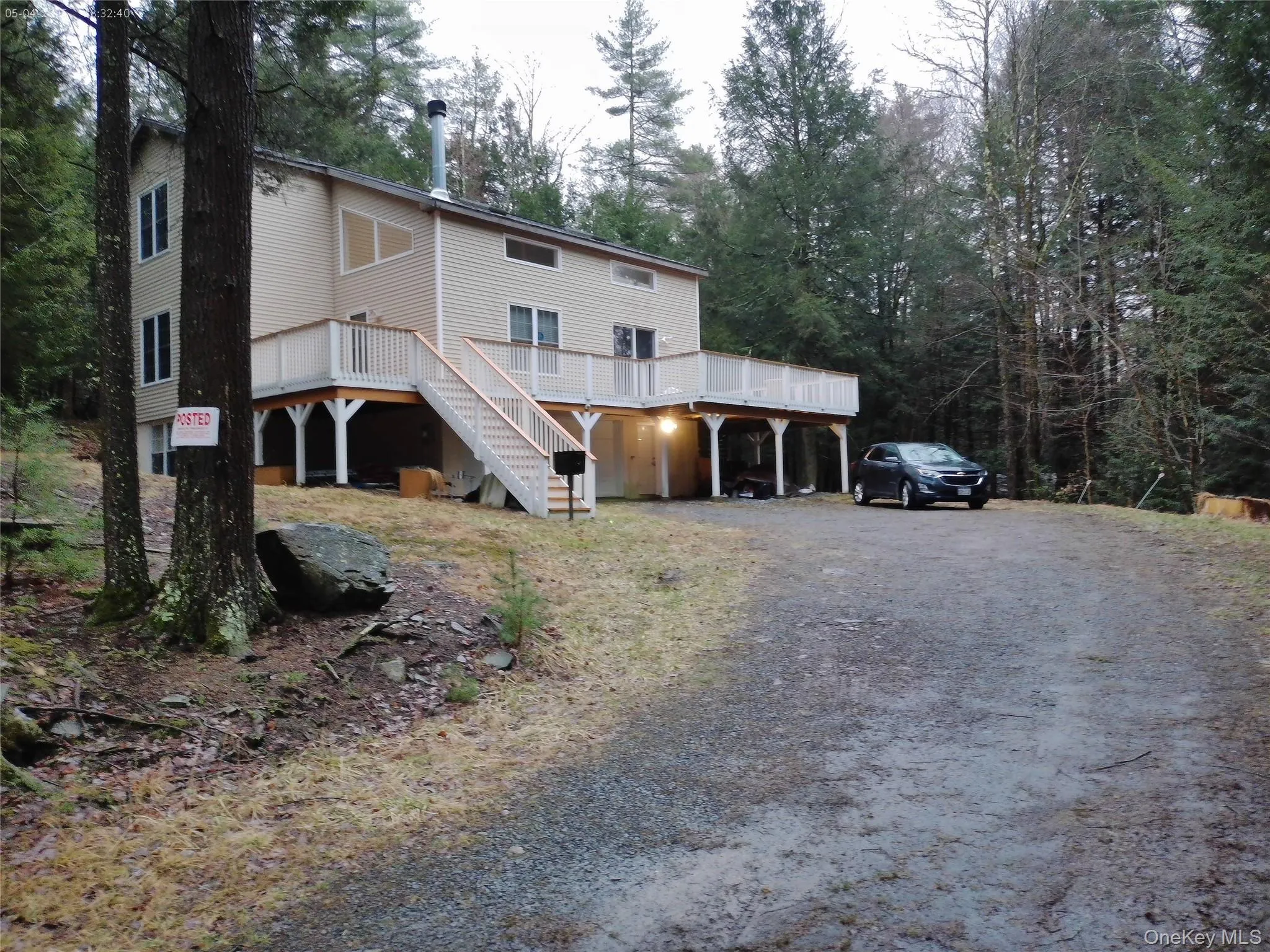 Rear view of house featuring gravel driveway, a deck, and stairs Rear view of house featuring gravel driveway, a deck, and stairs