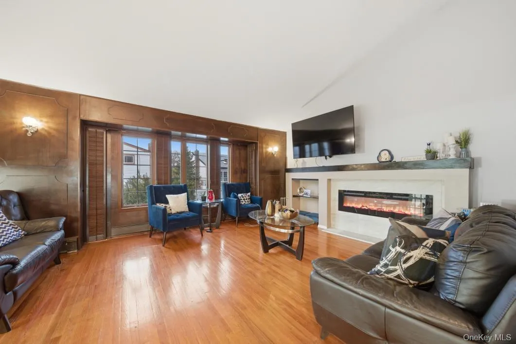 Living room featuring a glass covered fireplace, light wood style floors, wooden walls Living room featuring a glass covered fireplace, light wood style floors, wooden walls