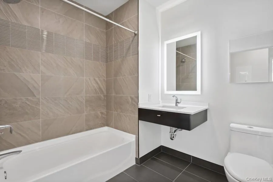 Full bathroom with sink, toilet, tile patterned flooring, and tiled shower / bath Full bathroom with sink, toilet, tile patterned flooring, and tiled shower / bath