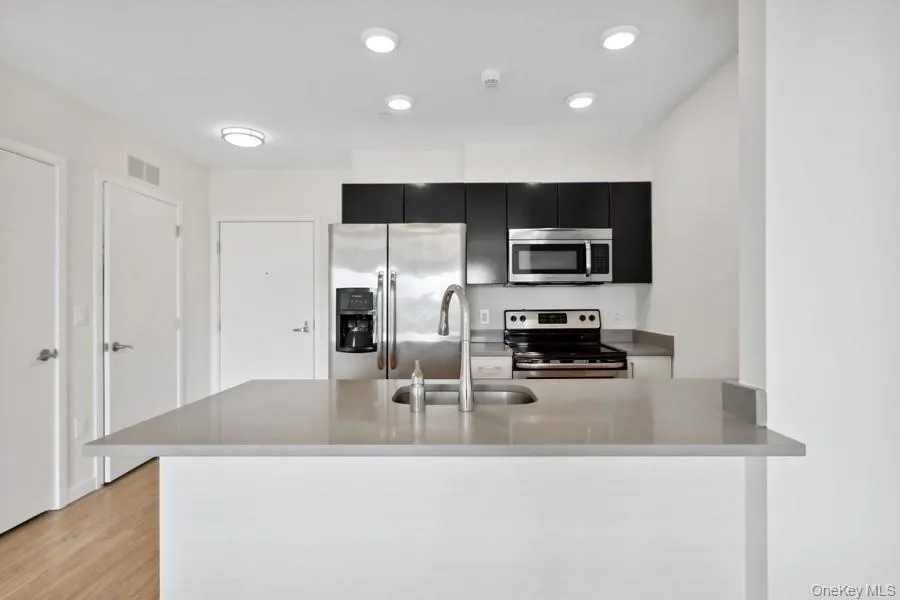 Kitchen with sink, stainless steel appliances, kitchen peninsula, and light hardwood / wood-style floors Kitchen with sink, stainless steel appliances, kitchen peninsula, and light hardwood / wood-style floors