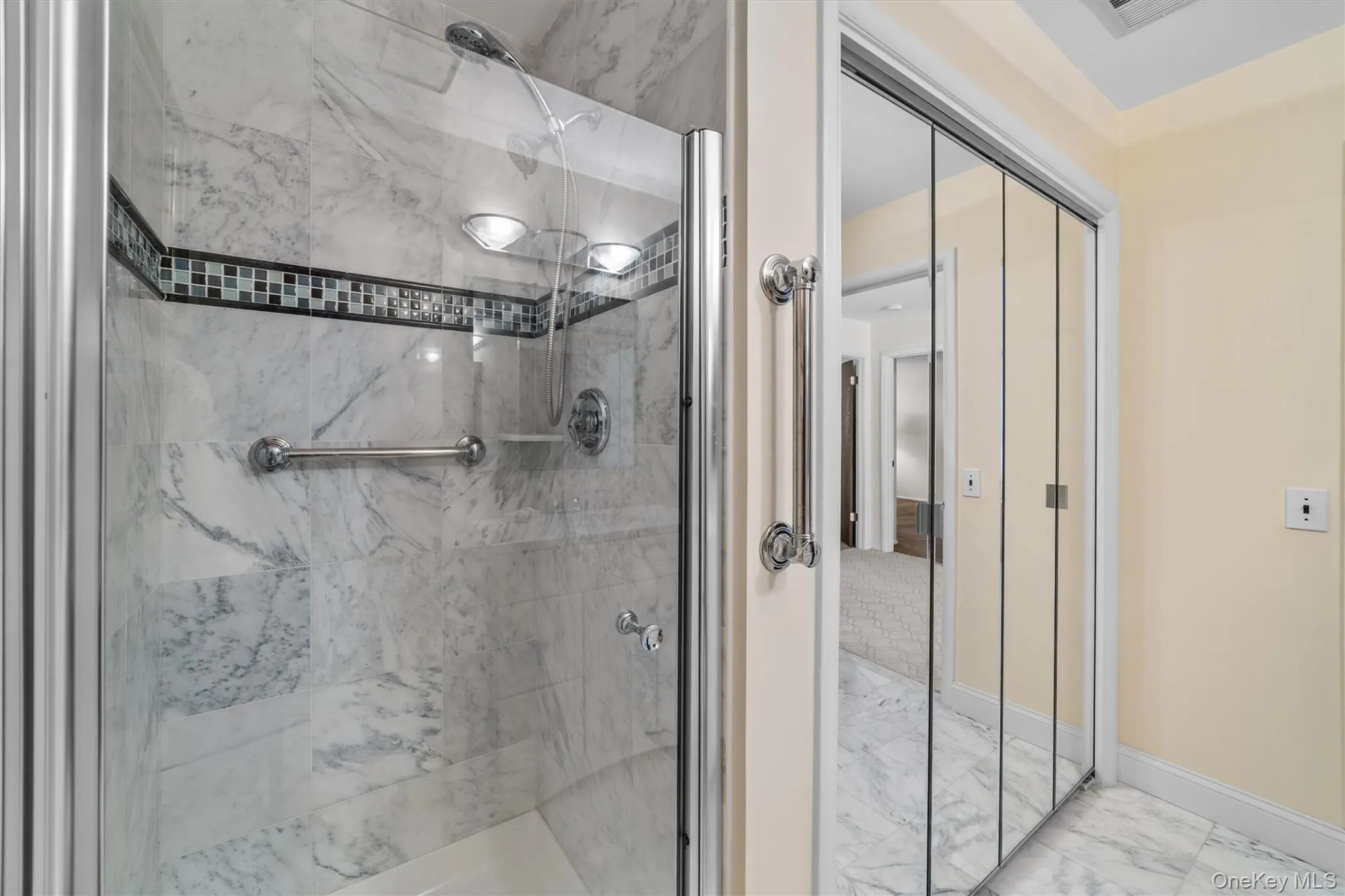 Beautiful Full Hall bath with marble like finish tiles wall and floor, stall shower and laundry behind glass doors. Beautiful Full Hall bath with marble like finish tiles wall and floor, stall shower and laundry behind glass doors.