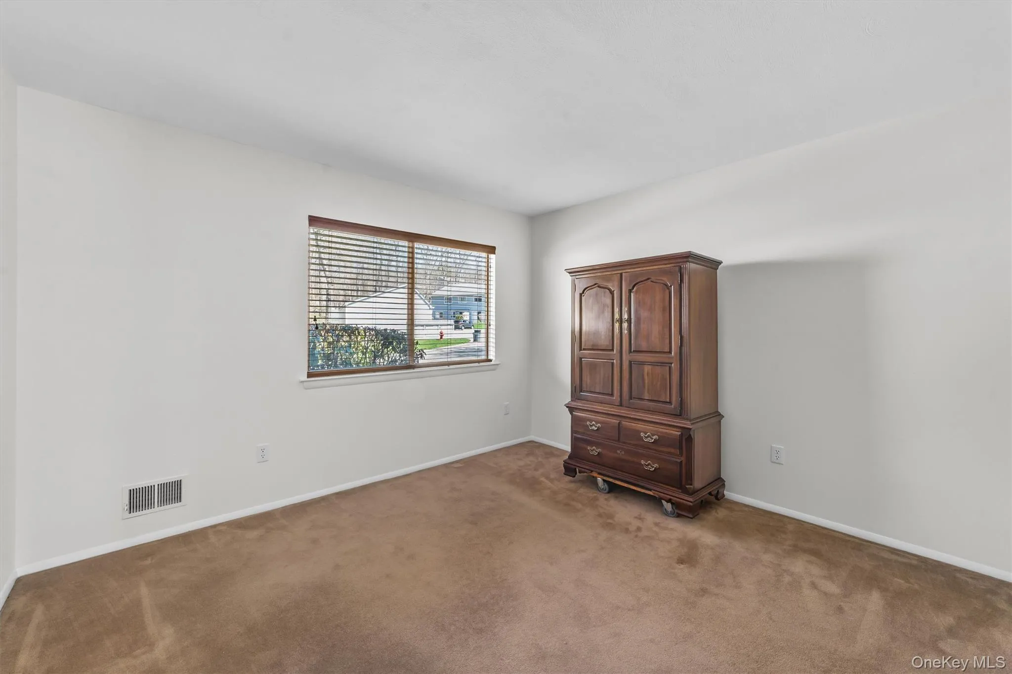 Carpeted spare room with large double window. Carpeted spare room with large double window.