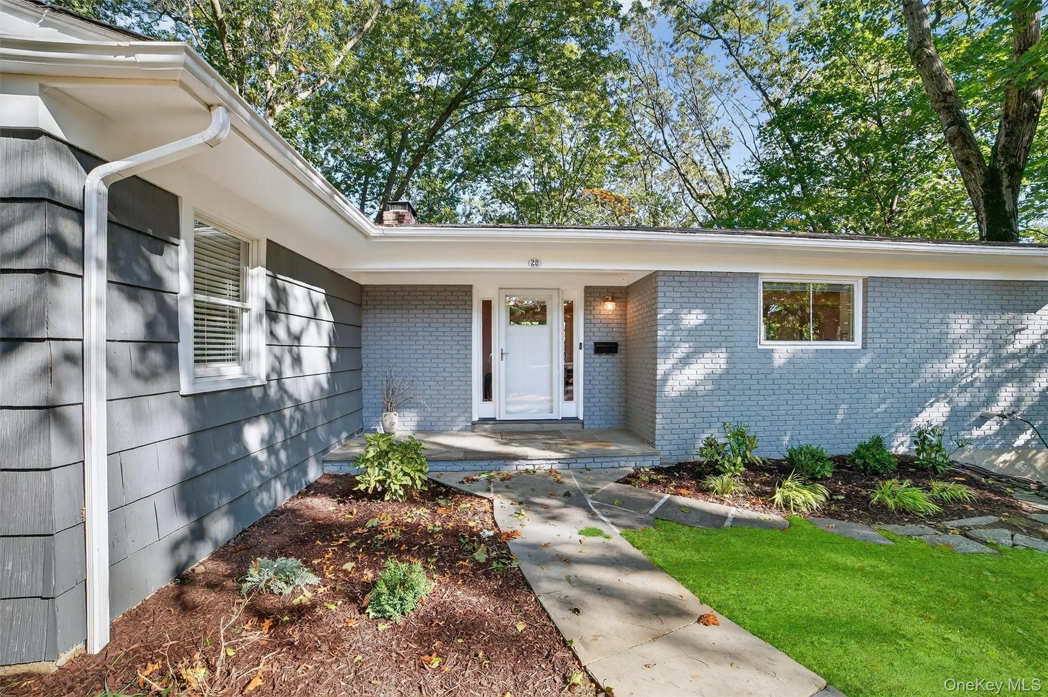 Doorway to property with brick siding, a chimney, and a lawn Doorway to property with brick siding, a chimney, and a lawn