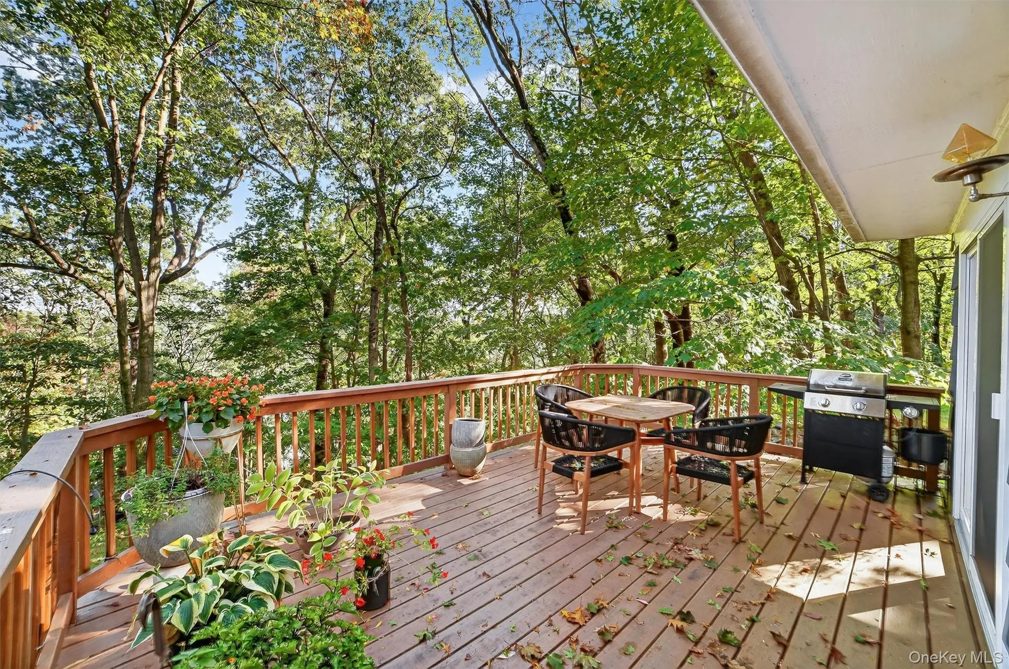 Wooden deck featuring outdoor dining area, view of wooded area, and a grill Wooden deck featuring outdoor dining area, view of wooded area, and a grill