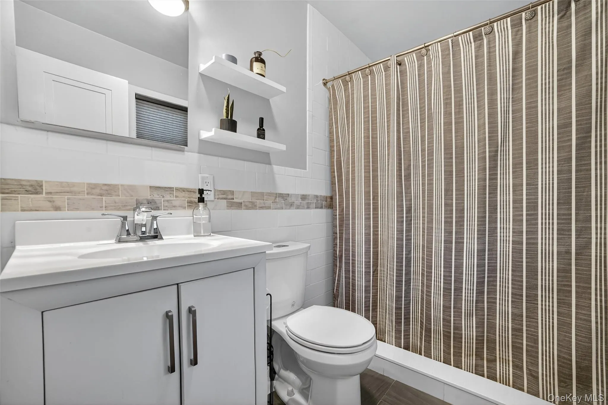 Full bath with vanity, tile walls, and a shower with shower curtain Full bath with vanity, tile walls, and a shower with shower curtain