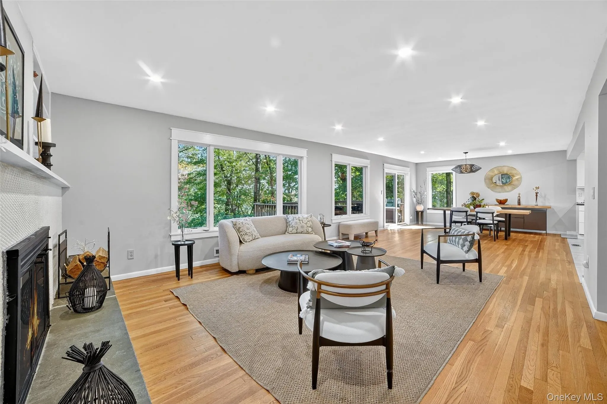 Living area featuring light wood-style flooring, a fireplace with flush hearth, and recessed lighting Living area featuring light wood-style flooring, a fireplace with flush hearth, and recessed lighting