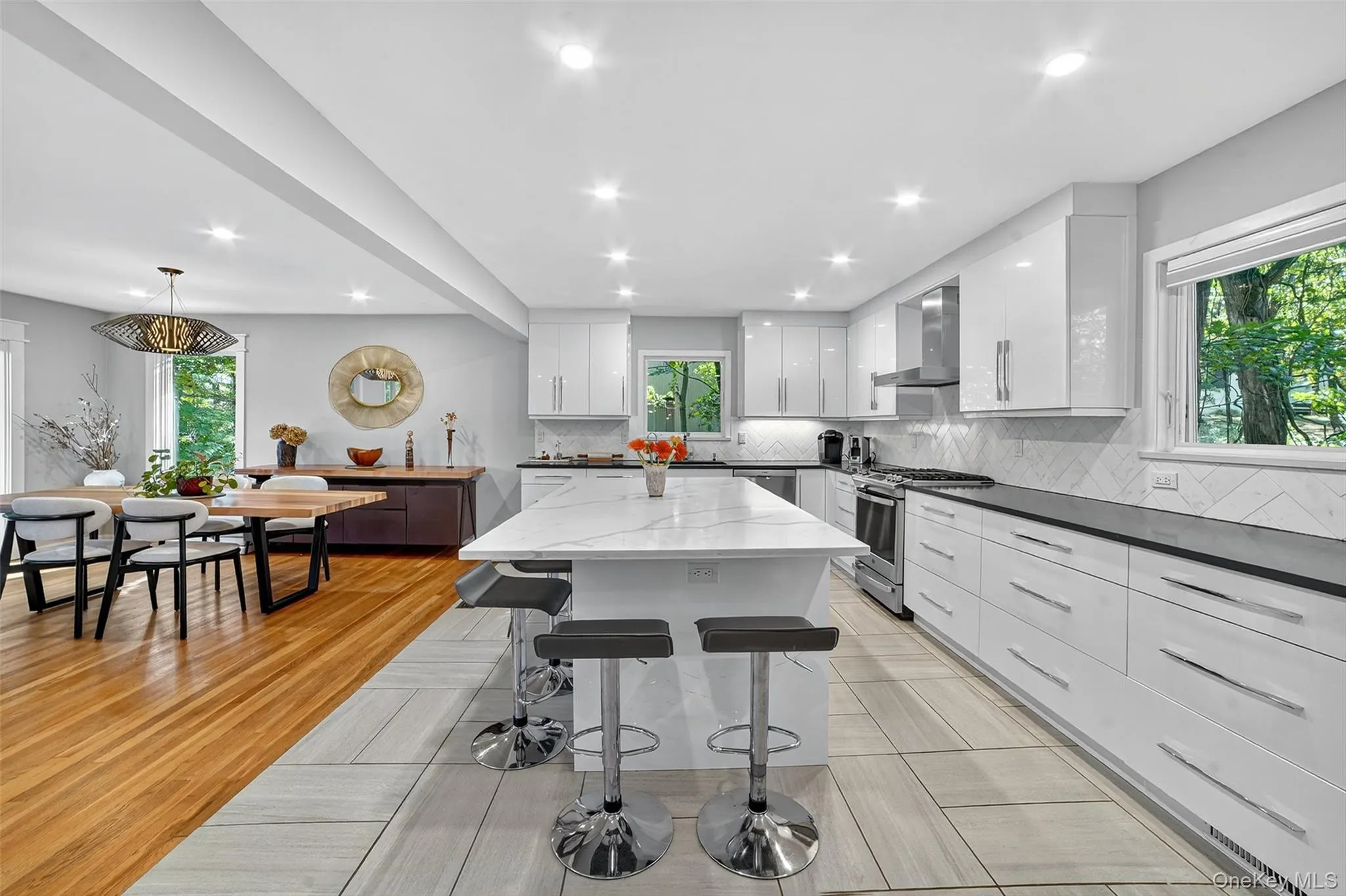 Kitchen with white cabinets, modern cabinets, stainless steel appliances, a breakfast bar area, and recessed lighting Kitchen with white cabinets, modern cabinets, stainless steel appliances, a breakfast bar area, and recessed lighting
