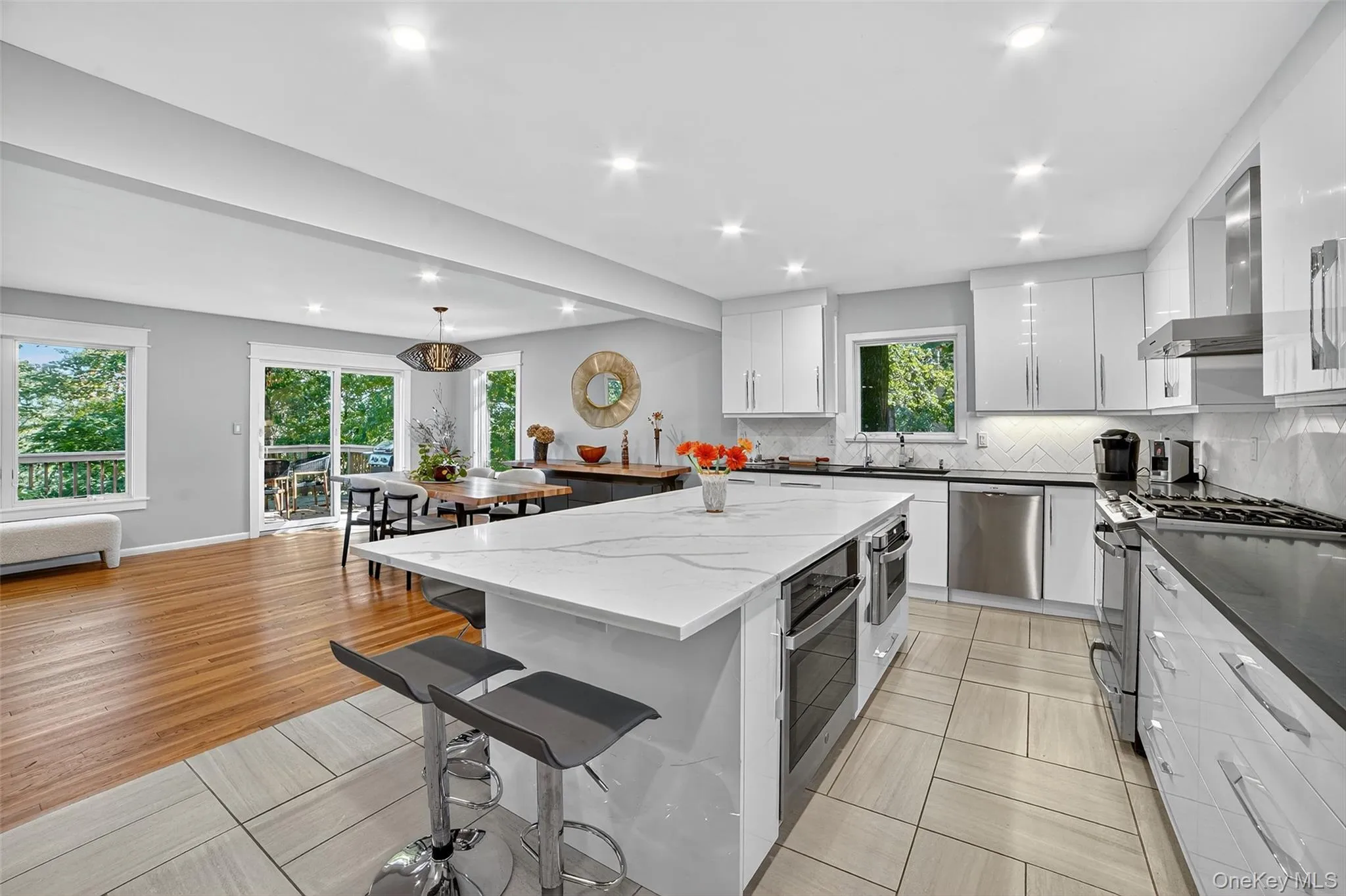 Kitchen with a kitchen bar, stainless steel appliances, dark stone counters, decorative backsplash, and white cabinetry Kitchen with a kitchen bar, stainless steel appliances, dark stone counters, decorative backsplash, and white cabinetry