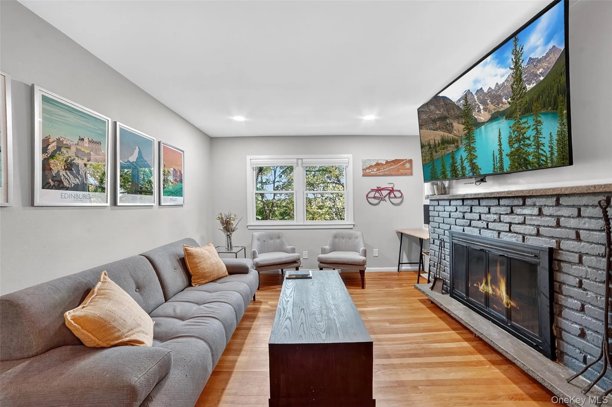 Living area featuring light wood-style floors, a brick fireplace, and recessed lighting Living area featuring light wood-style floors, a brick fireplace, and recessed lighting