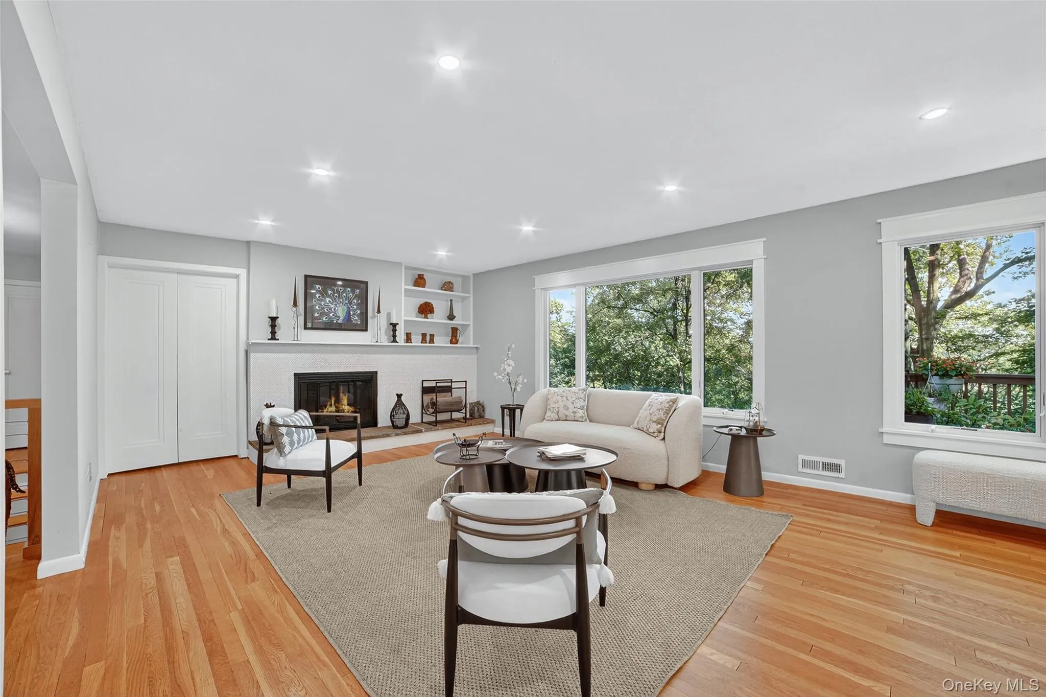 Living area with light wood-style floors, radiator, a brick fireplace, recessed lighting, and built in features Living area with light wood-style floors, radiator, a brick fireplace, recessed lighting, and built in features