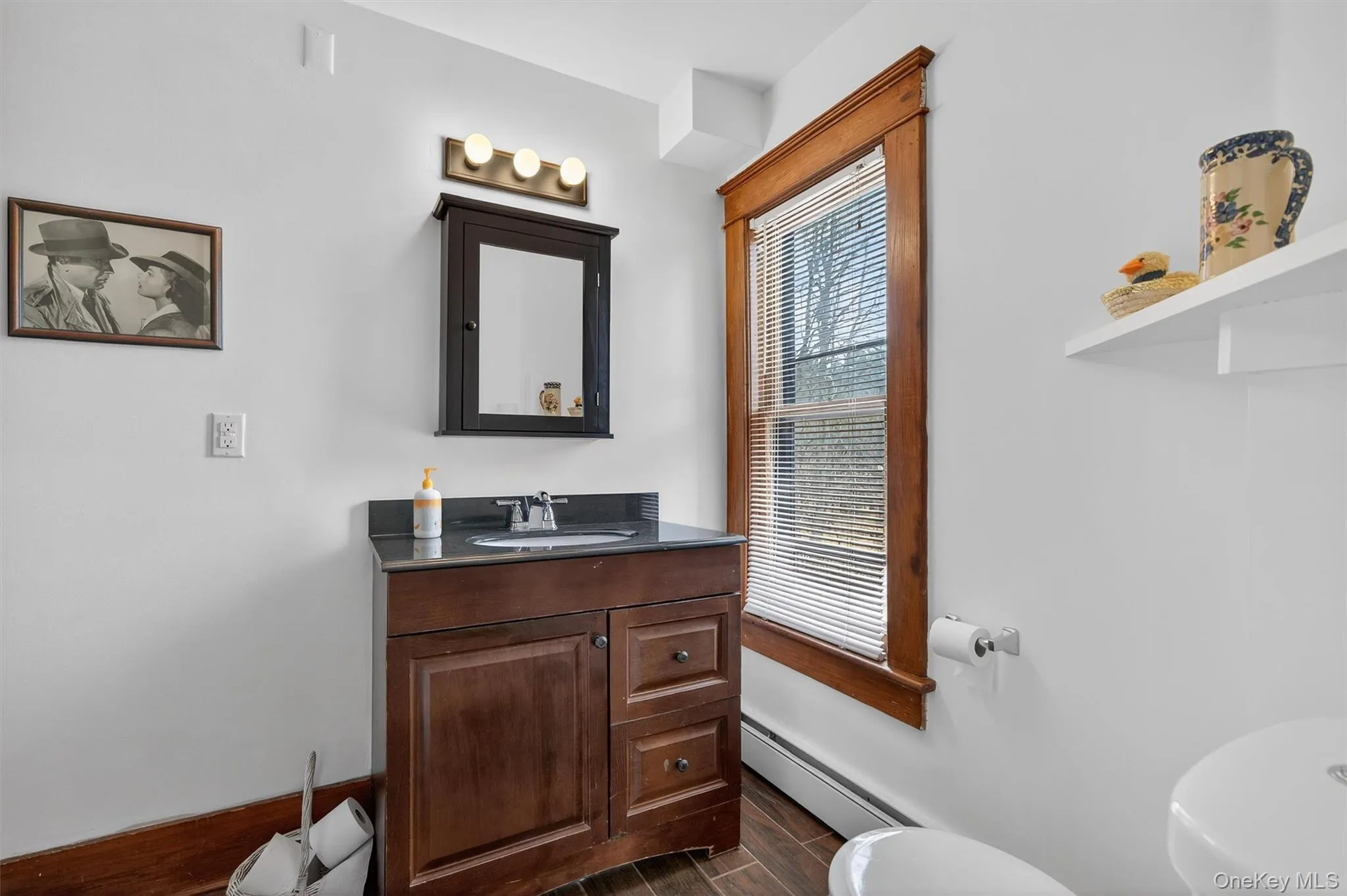 Bathroom with vanity, baseboard heating, and wood finish floors Bathroom with vanity, baseboard heating, and wood finish floors