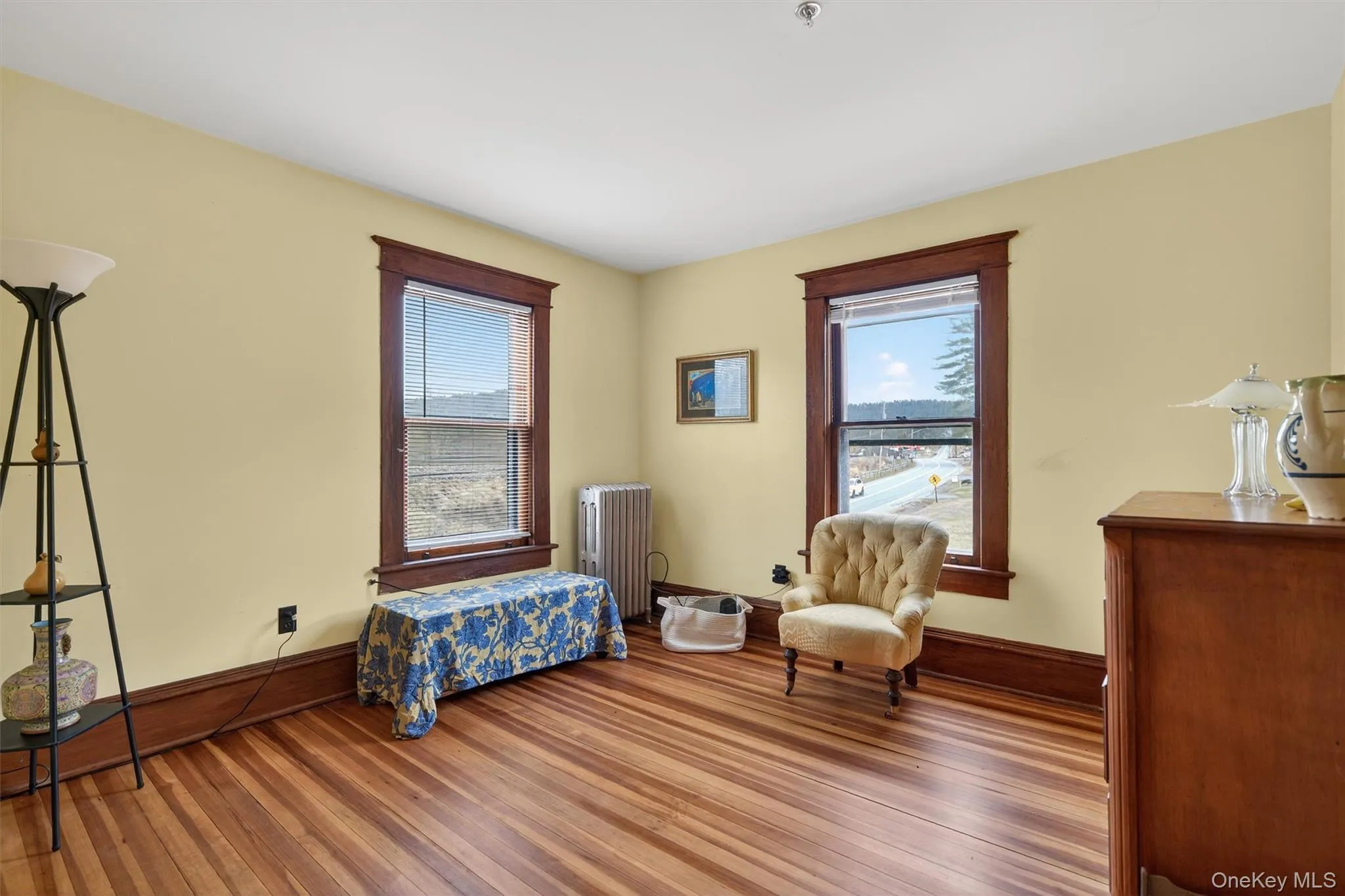 Bedroom featuring radiator, wood finished floors, and multiple windows Bedroom featuring radiator, wood finished floors, and multiple windows
