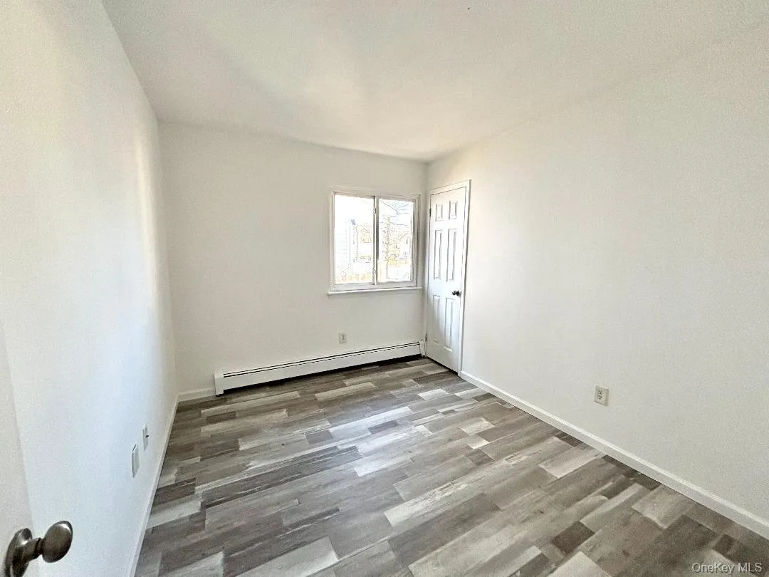 Third bedroom with a baseboard radiator and vinyl wood-style floors Third bedroom with a baseboard radiator and vinyl wood-style floors