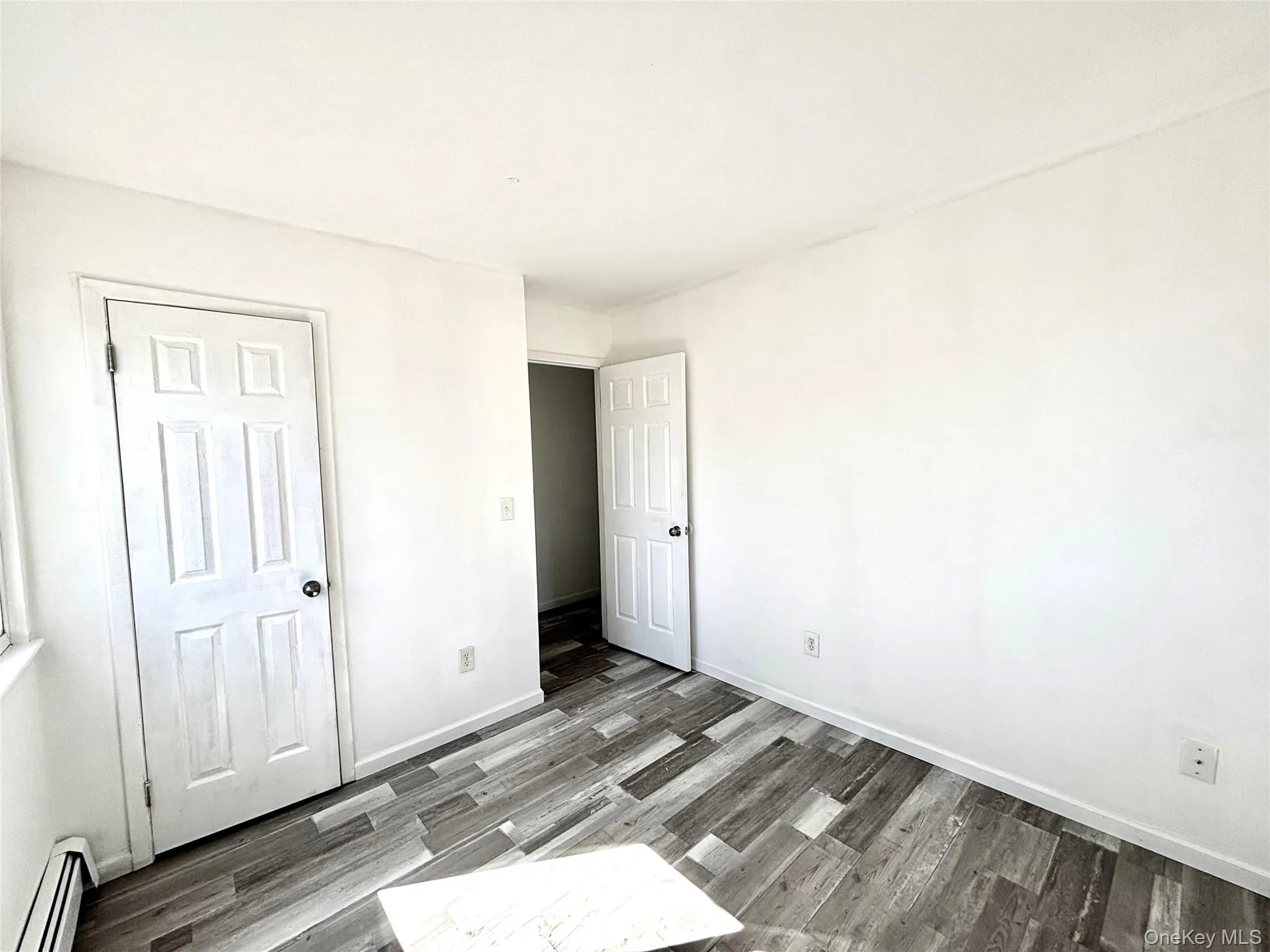 Second bedroom with a baseboard radiator and vinyl wood-style floors Second bedroom with a baseboard radiator and vinyl wood-style floors