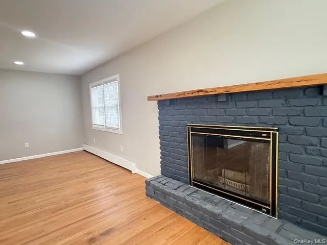 wood finished floors, recessed lighting, and a brick fireplace wood finished floors, recessed lighting, and a brick fireplace
