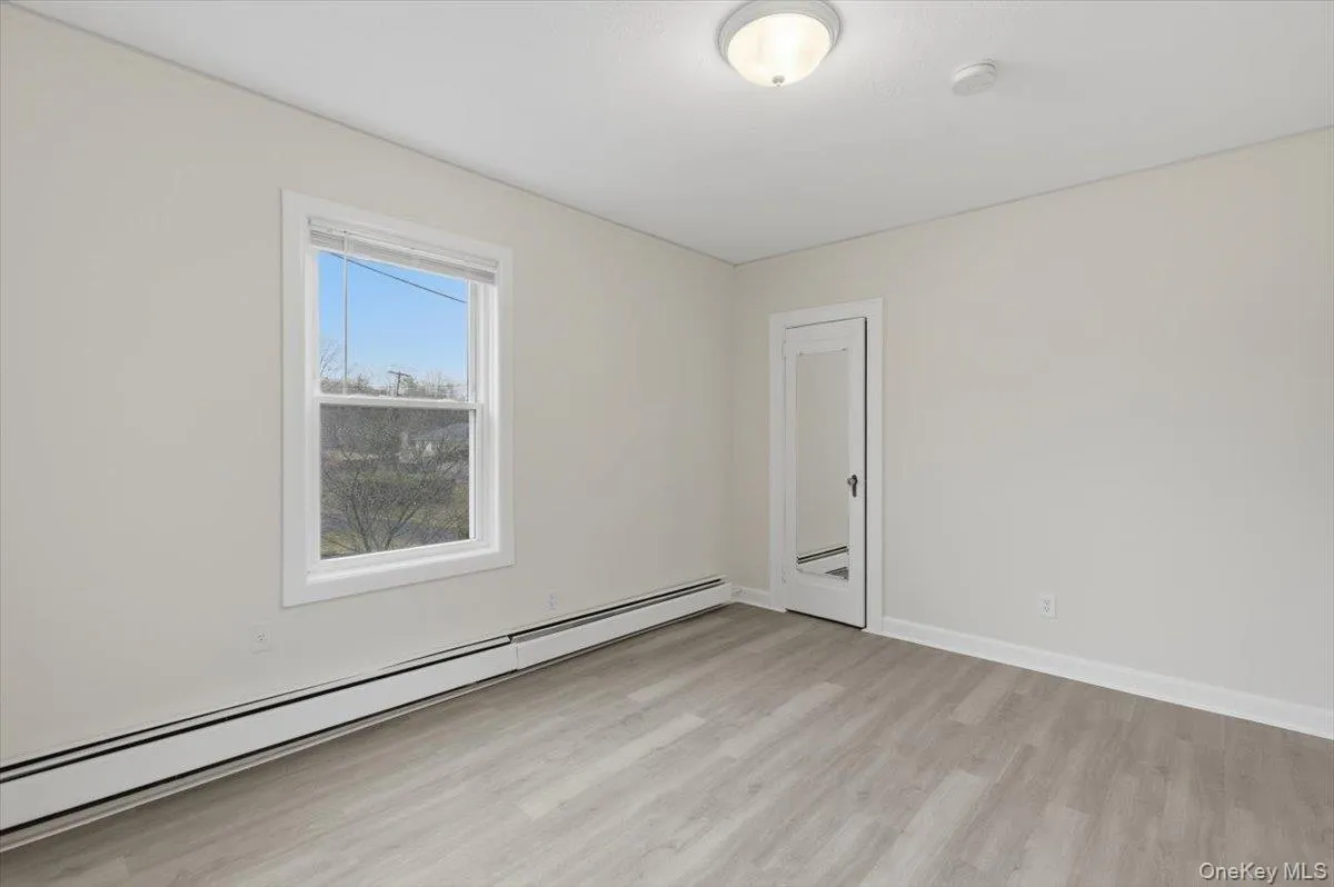 Unfurnished room featuring a baseboard heating unit and light wood-style floors Unfurnished room featuring a baseboard heating unit and light wood-style floors