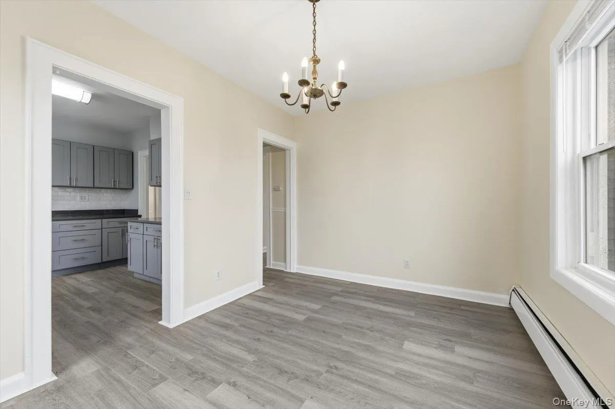 Unfurnished dining area with baseboard heating, hanging lights, light wood finished floors, and plenty of natural light Unfurnished dining area with baseboard heating, hanging lights, light wood finished floors, and plenty of natural light