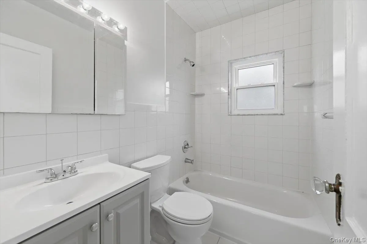 Bathroom featuring vanity, bathtub / shower combination, and tile walls Bathroom featuring vanity, bathtub / shower combination, and tile walls
