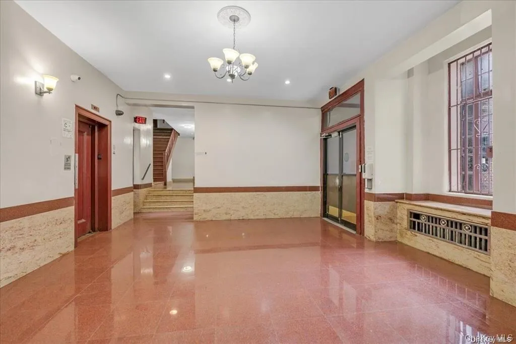 Unfurnished room featuring wainscoting, granite tiled floors, elevator, tile walls, and a chandelier Unfurnished room featuring wainscoting, granite tiled floors, elevator, tile walls, and a chandelier