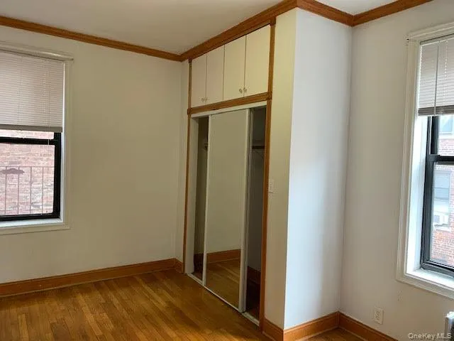 Unfurnished bedroom with crown molding, light wood-style flooring, and a closet Unfurnished bedroom with crown molding, light wood-style flooring, and a closet